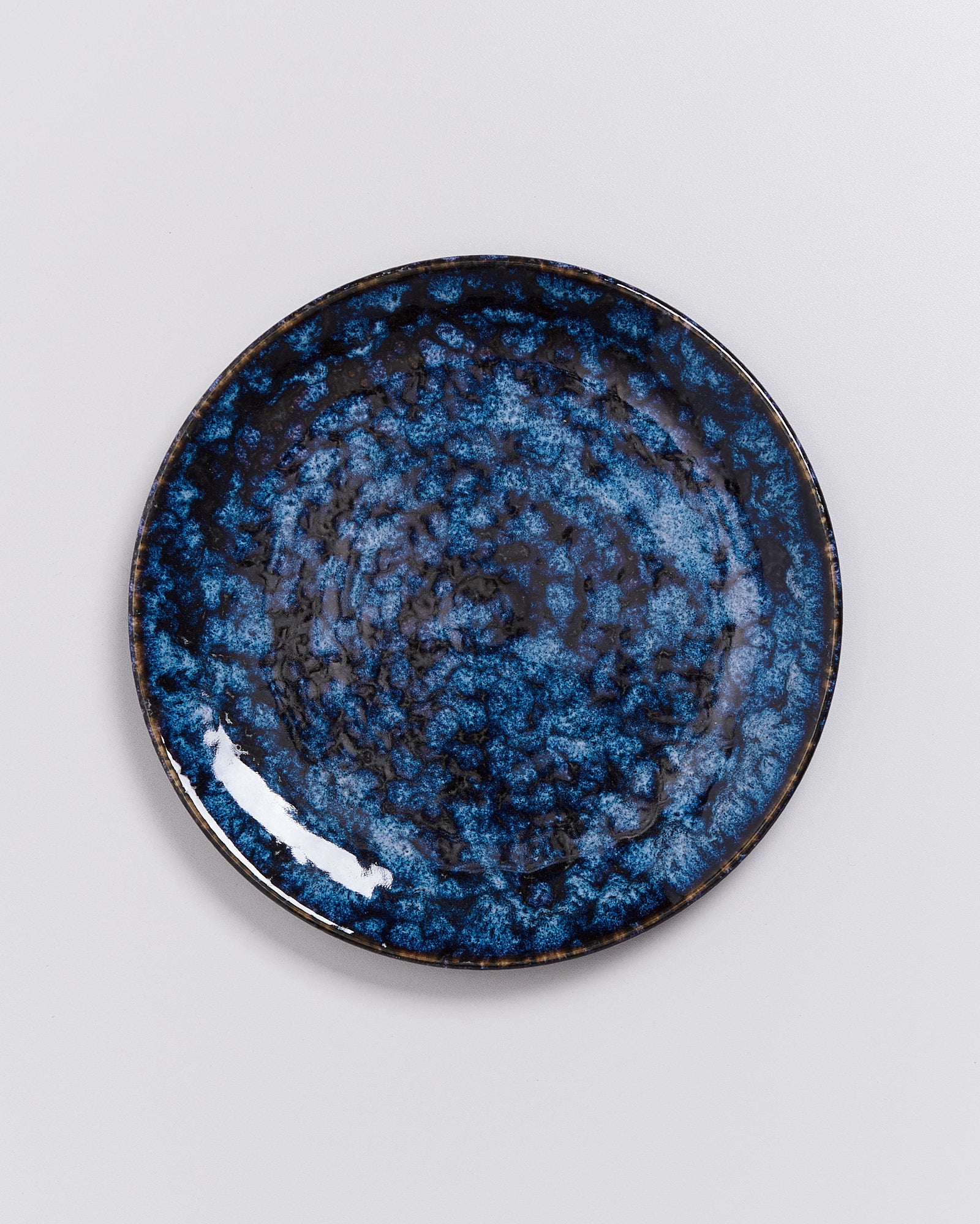 Dunkelblauer Teller mit marmoriertem Muster auf weißem Hintergrund.