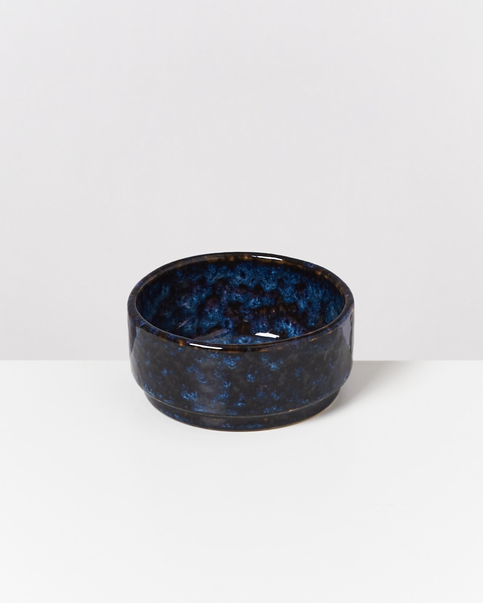 Dunkelblaue, keramikartige Schale mit gemustertem Design auf einem weißen Hintergrund.