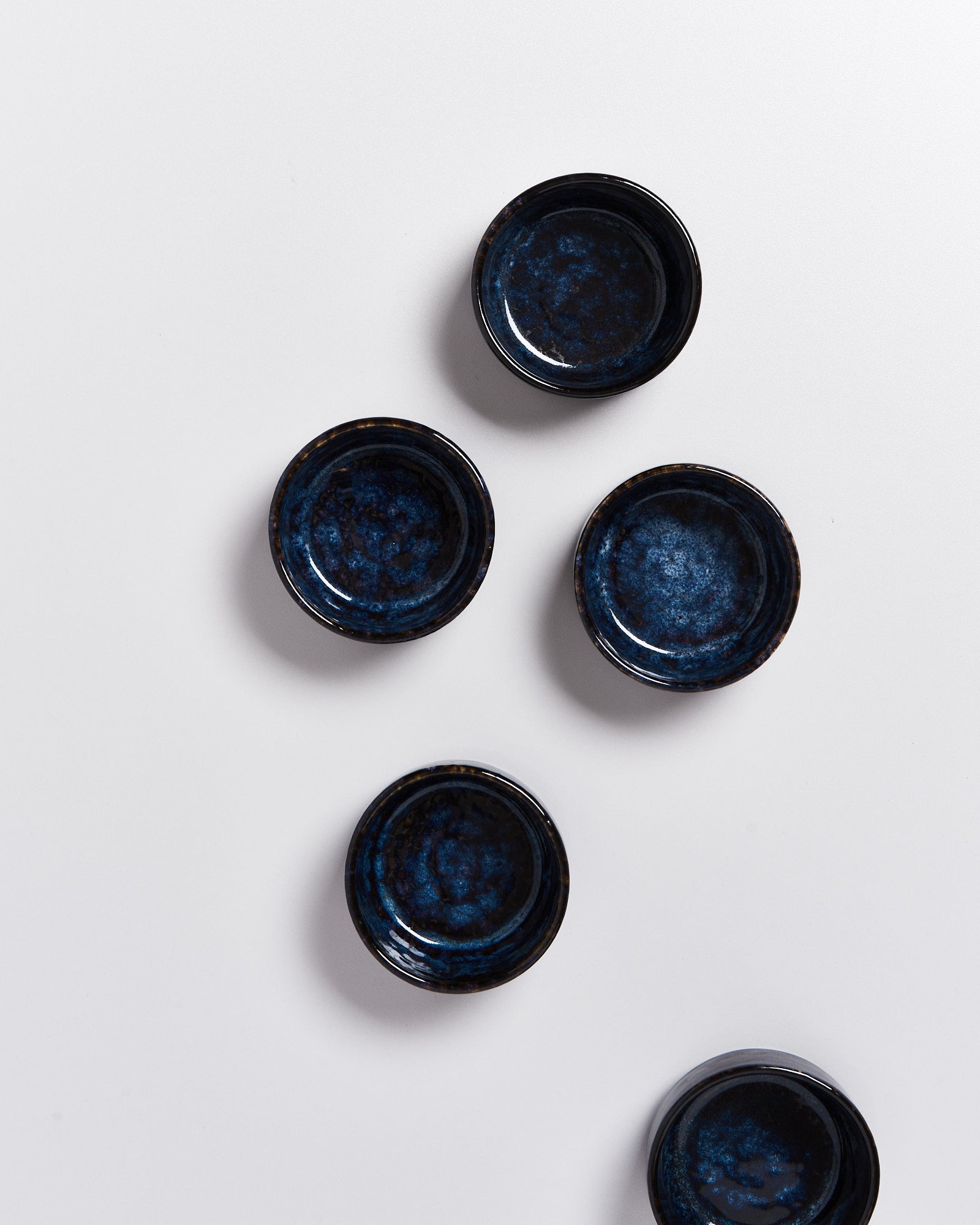 Fünf blaue, runde Schalen mit marmoriertem Muster auf einem weißen Hintergrund angeordnet.