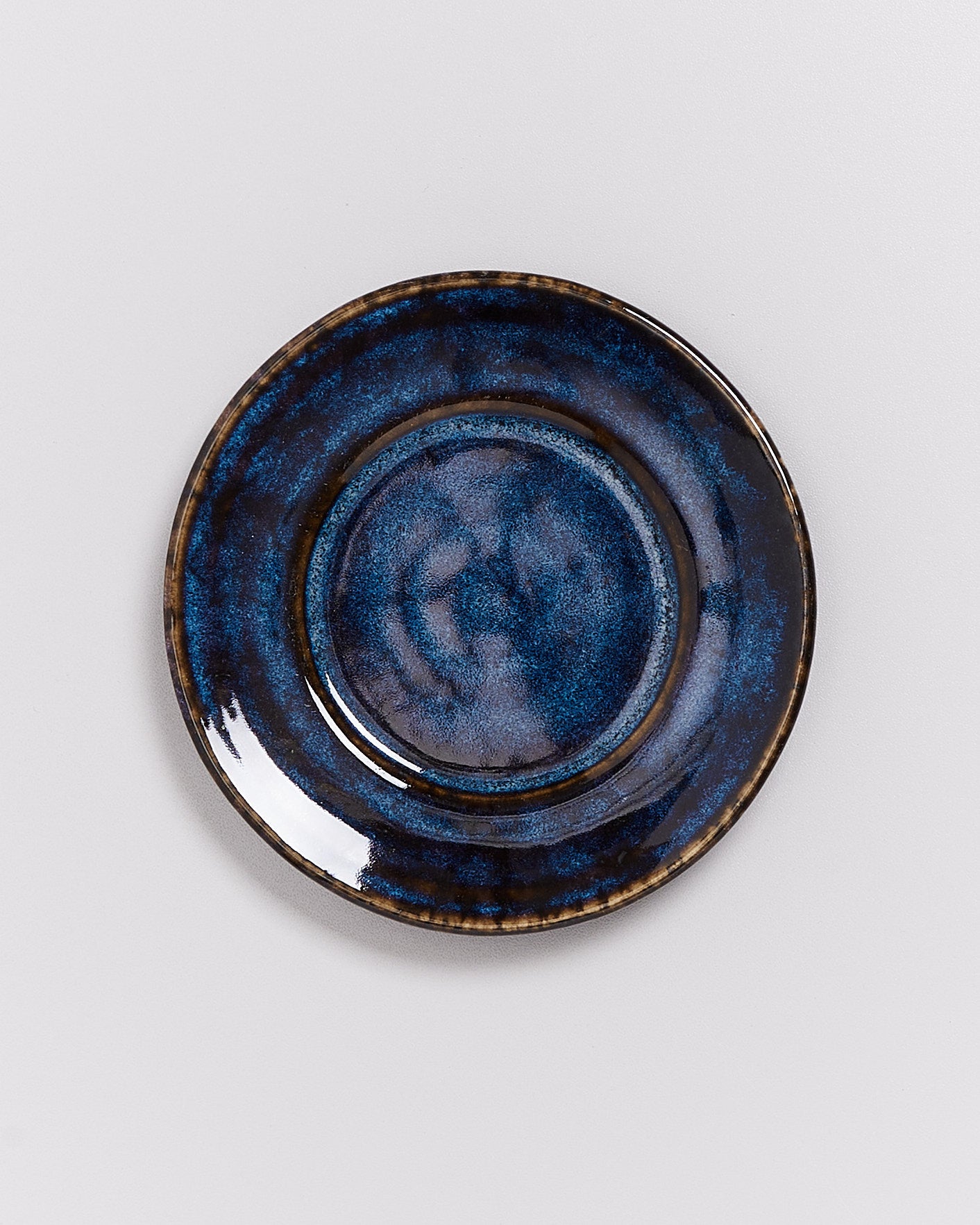 Dunkelblauer, glasiert Teller mit unregelmäßigem Muster auf hellem Hintergrund.