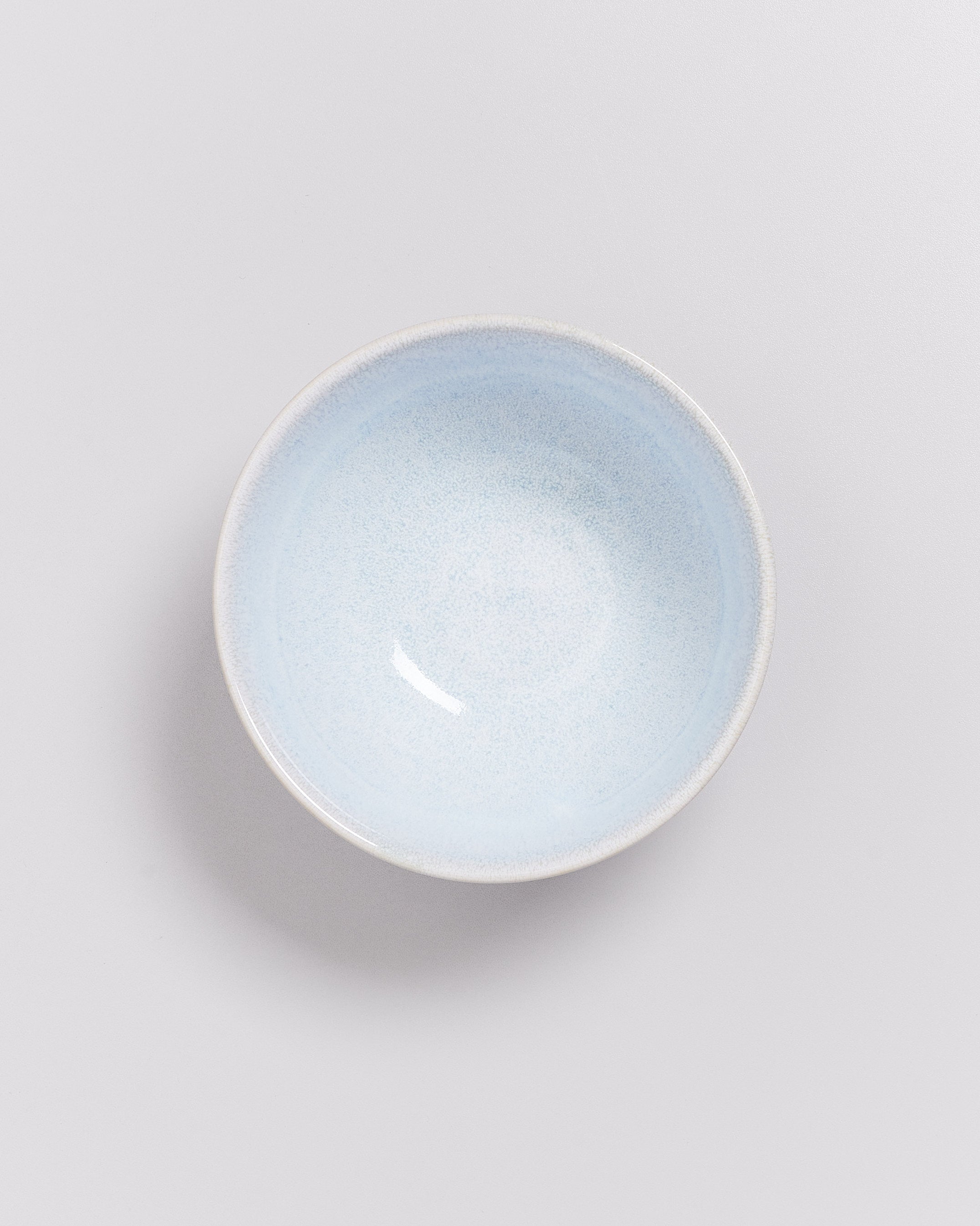 Hellblaue, runde Schüssel von oben betrachtet auf weißem Hintergrund.