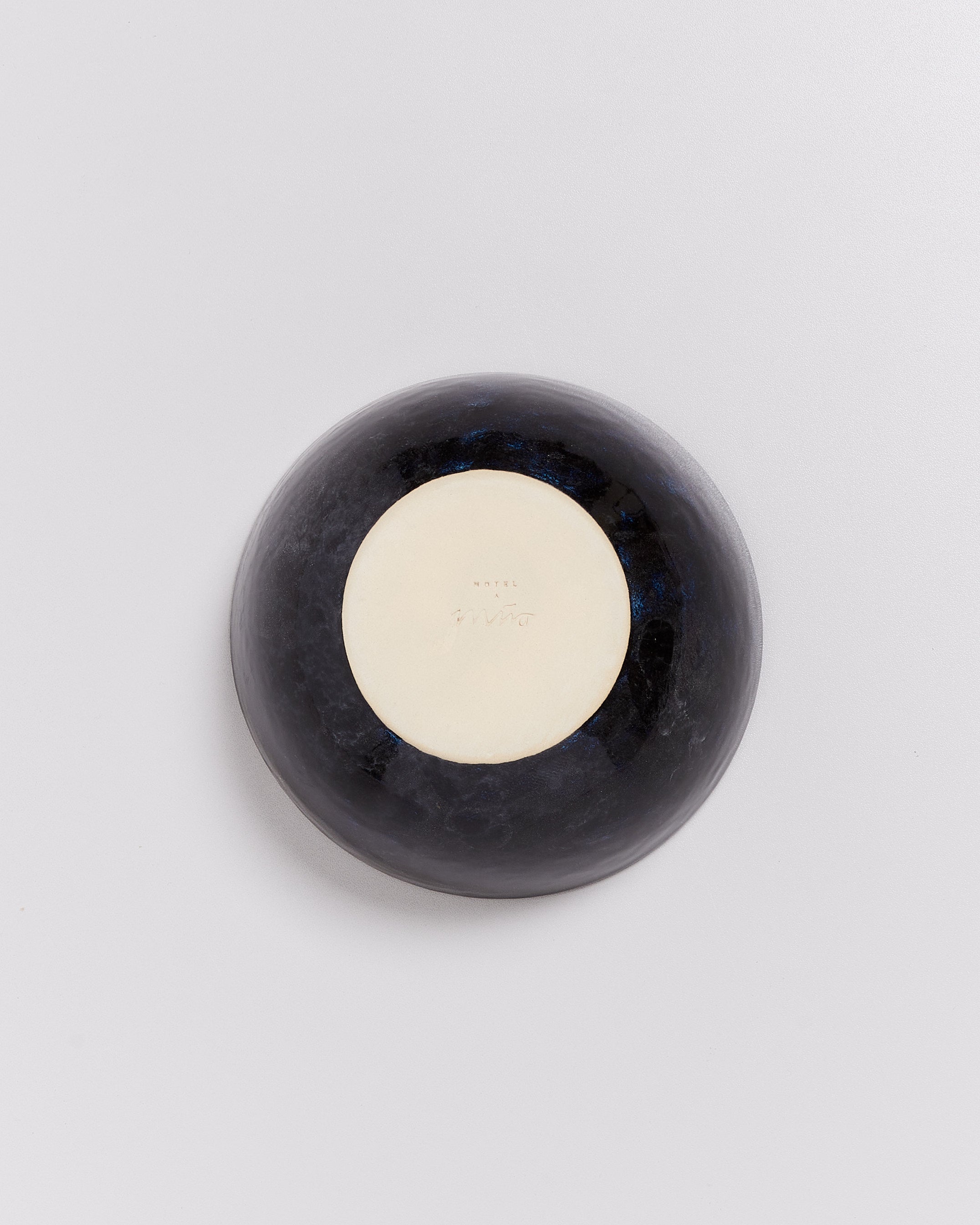 Schwarze Schale auf weißem Hintergrund, mit einer hellen kreisförmigen Fläche in der Mitte.