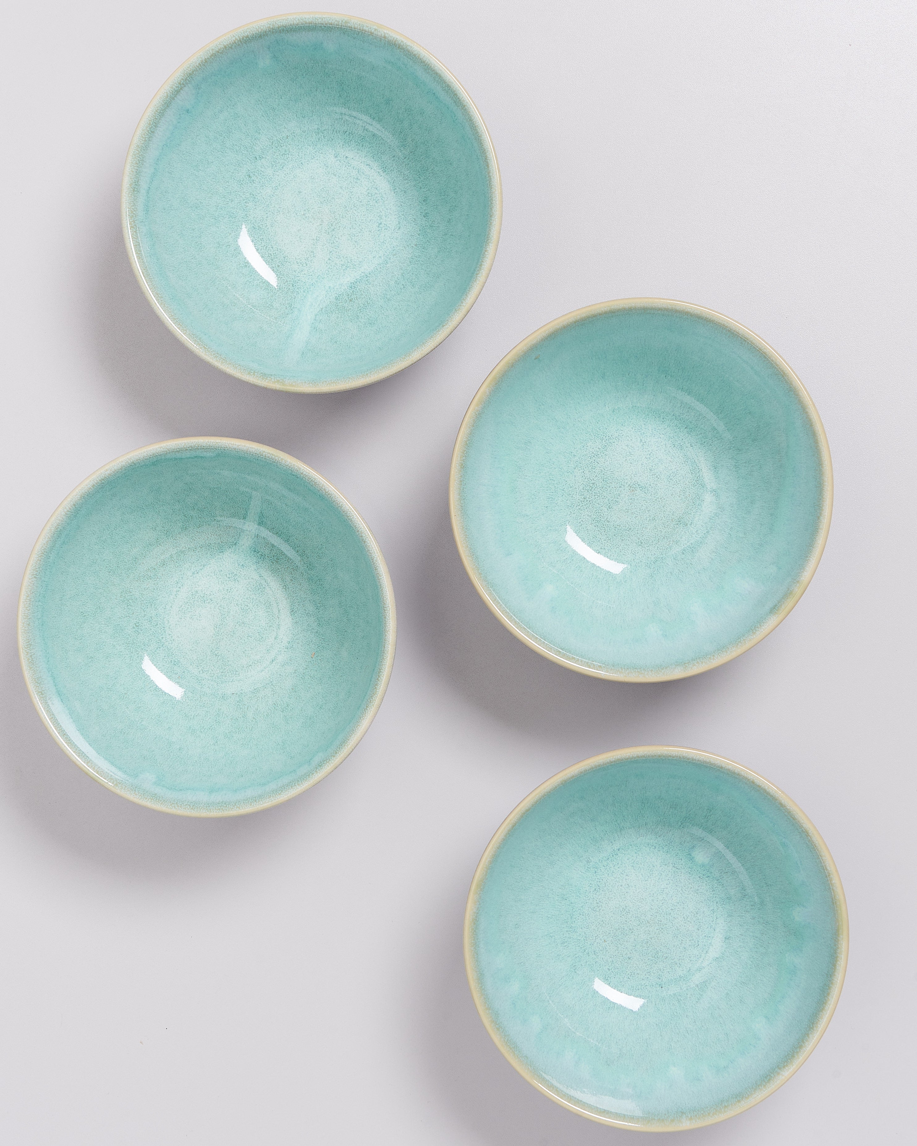 Vier türkisfarbene Schalen auf hellem Hintergrund, von oben fotografiert.