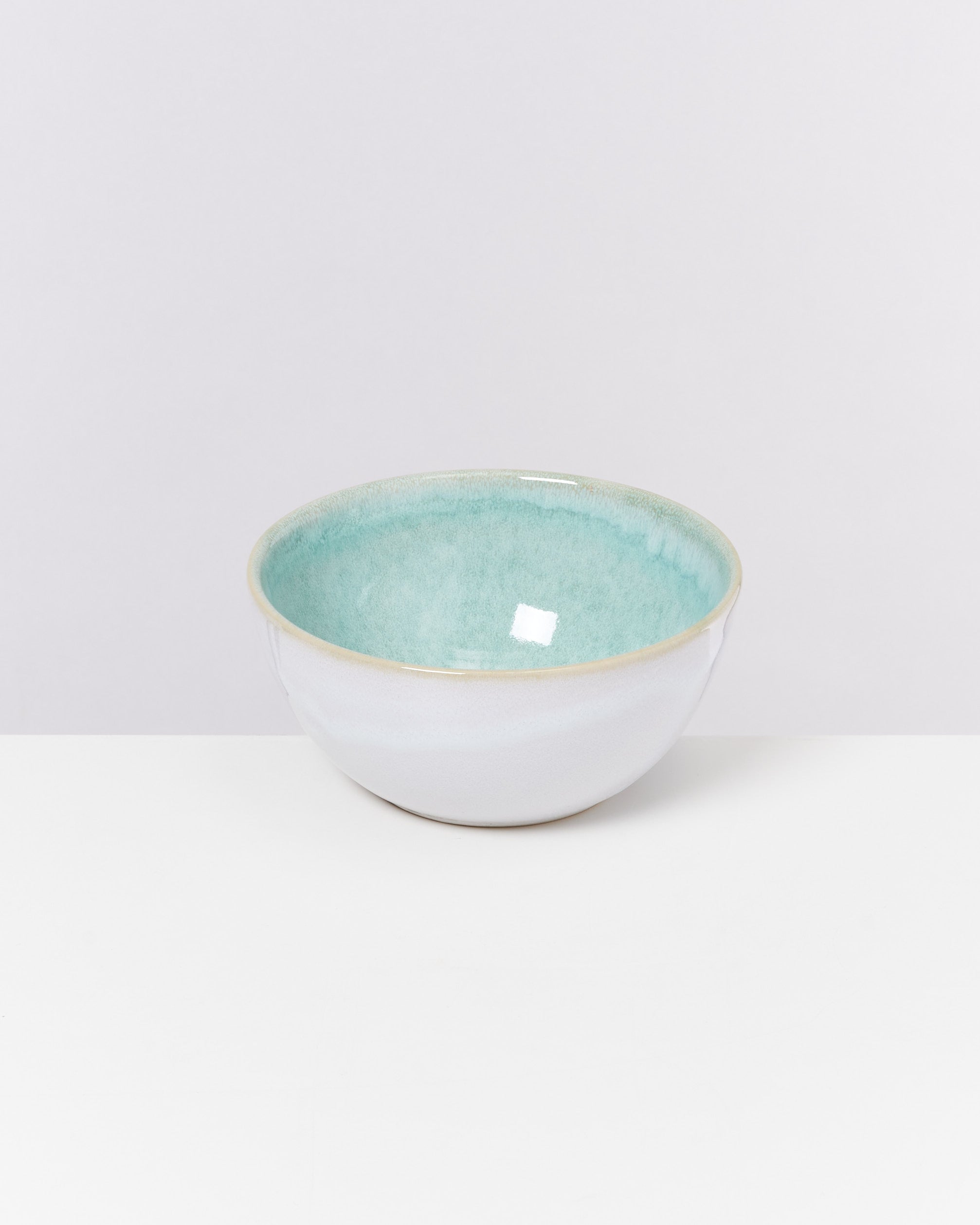 Keramikschale mit blauem Inneren und weißem Äußeren auf weißem Hintergrund.