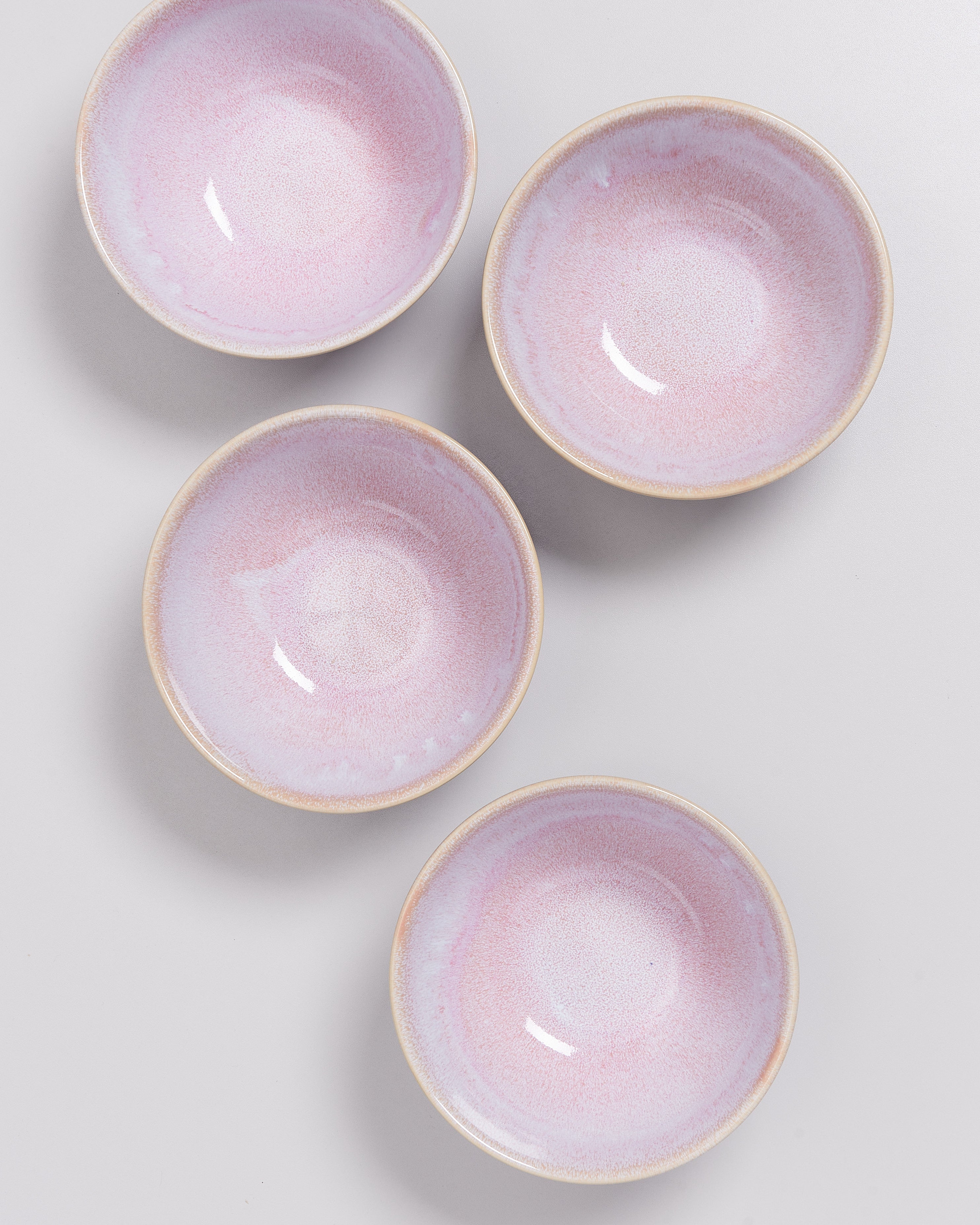 Vier rosa Schalen mit zartem Farbverlauf auf einer grauen Oberfläche.