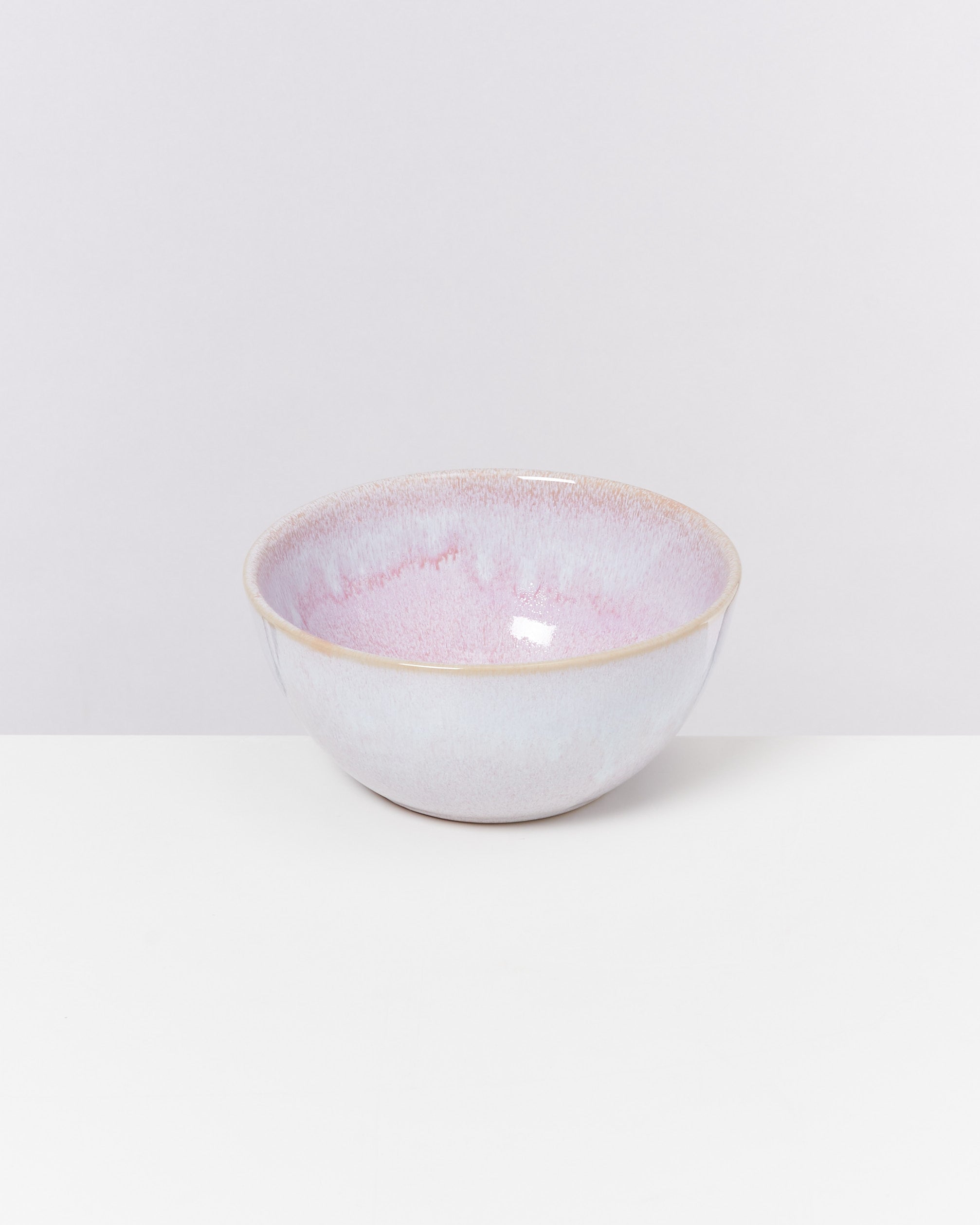 Keramikschüssel mit pastellrosa und lila Glasur auf weißem Hintergrund.