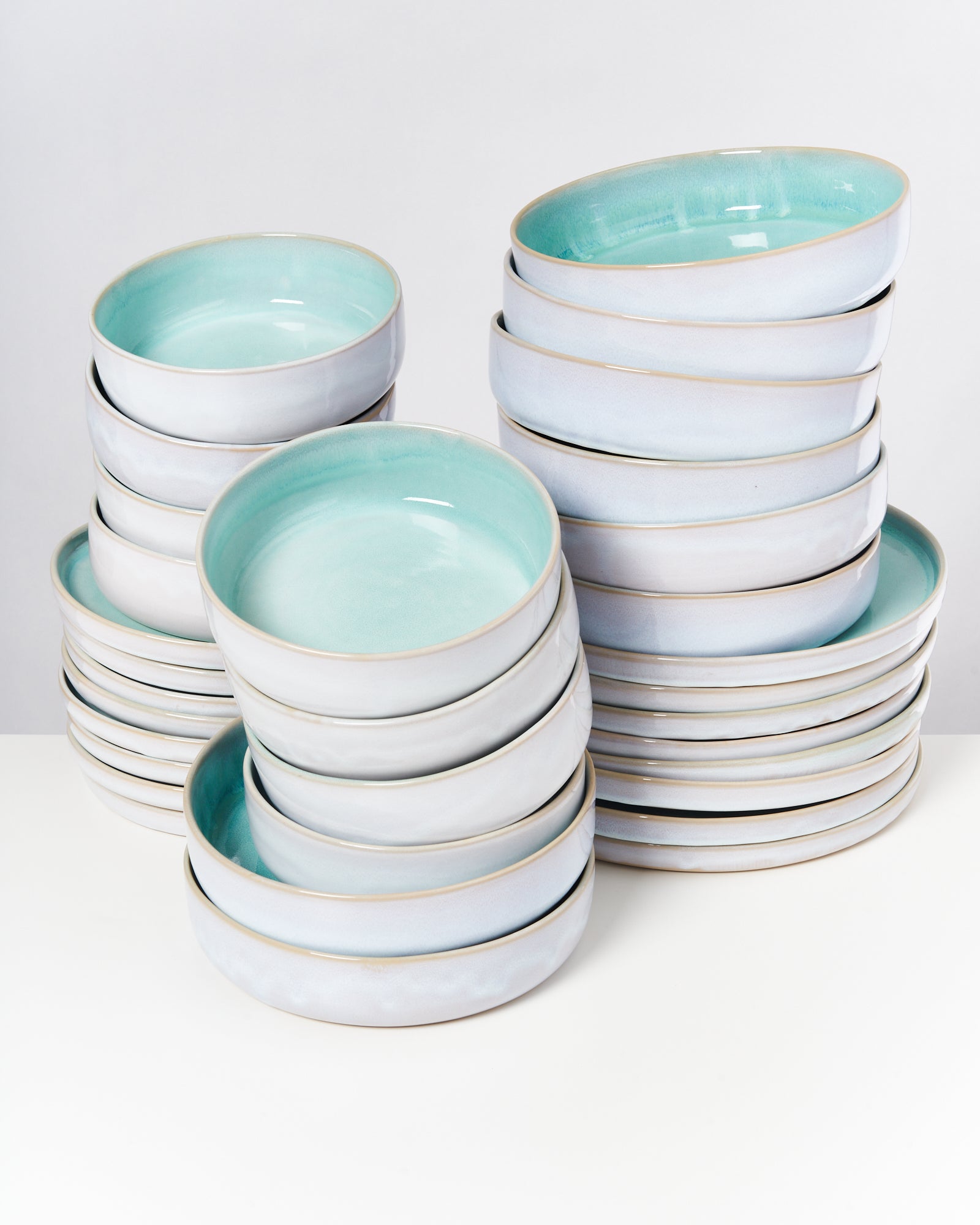 Gestapelte Keramikteller mit blauer Innenseite auf einem weißen Hintergrund.