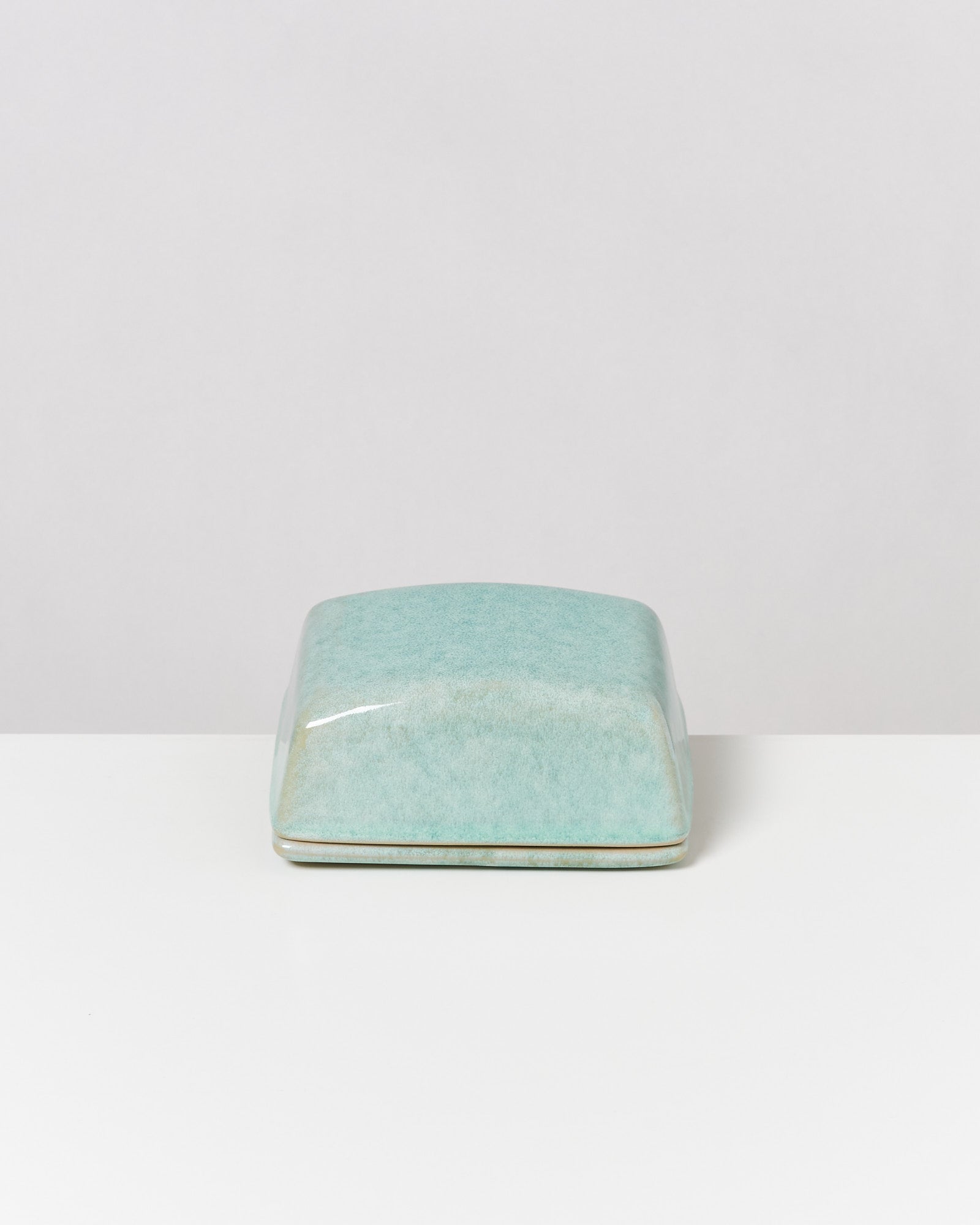 Rechteckige, türkisfarbene, glatte Box mit gewölbtem Deckel auf weißem Hintergrund.