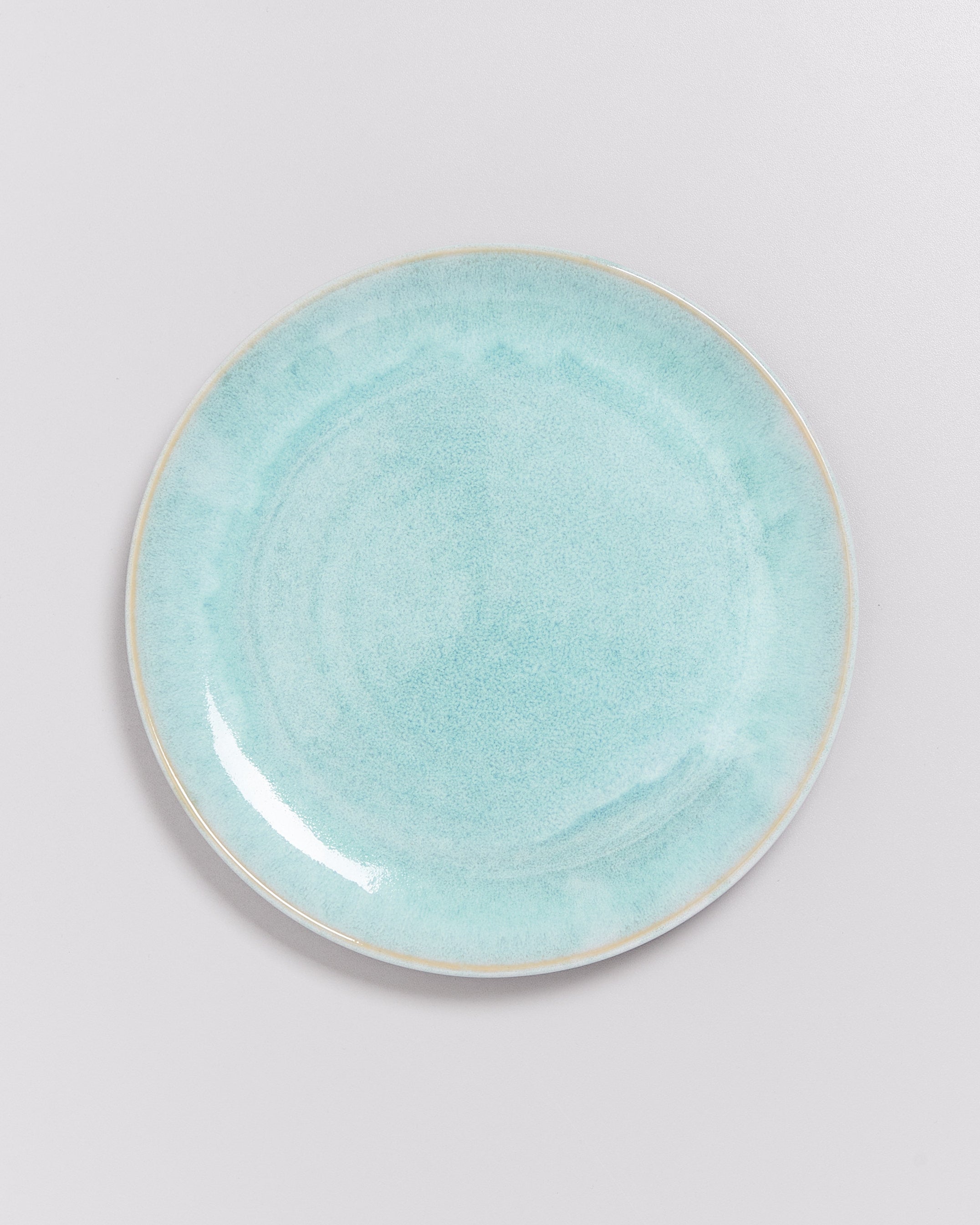 Ein hellblauer, runder Keramikteller auf einem weißen Hintergrund.