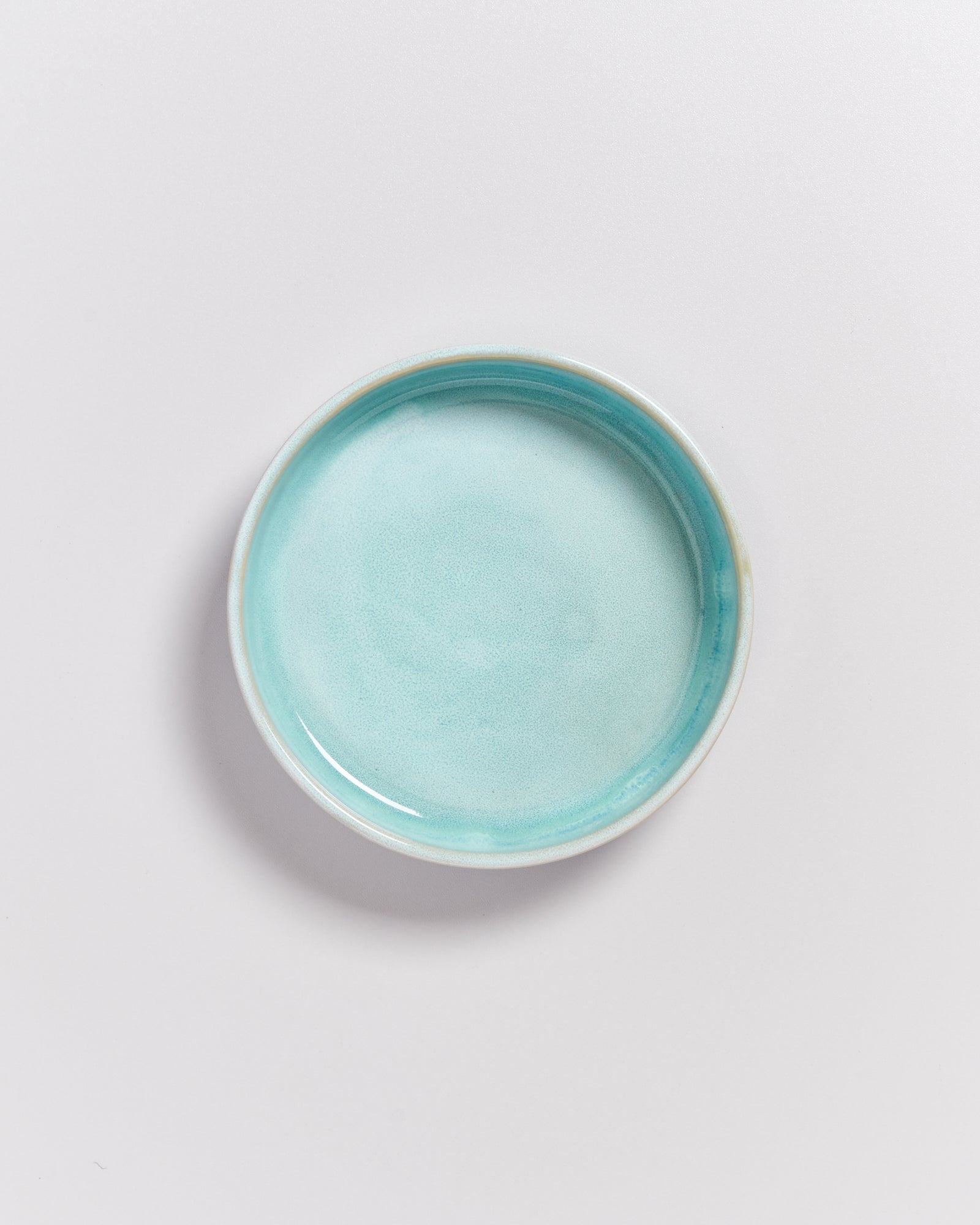 Ein rundes, hellblaues Keramikschälchen auf einer weißen Oberfläche.