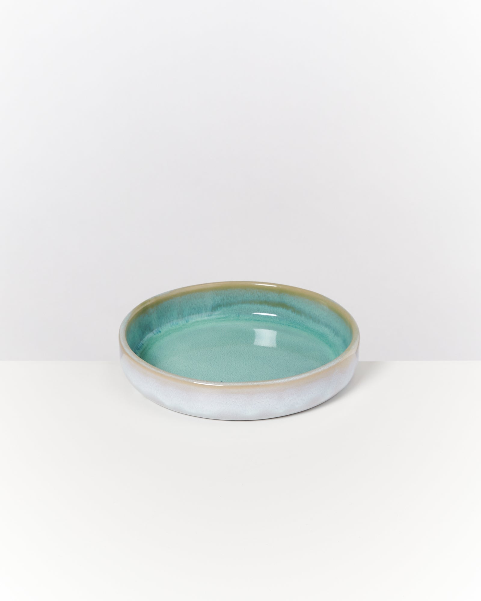 Keramikschale mit türkisblauer Glasur auf weißem Hintergrund.