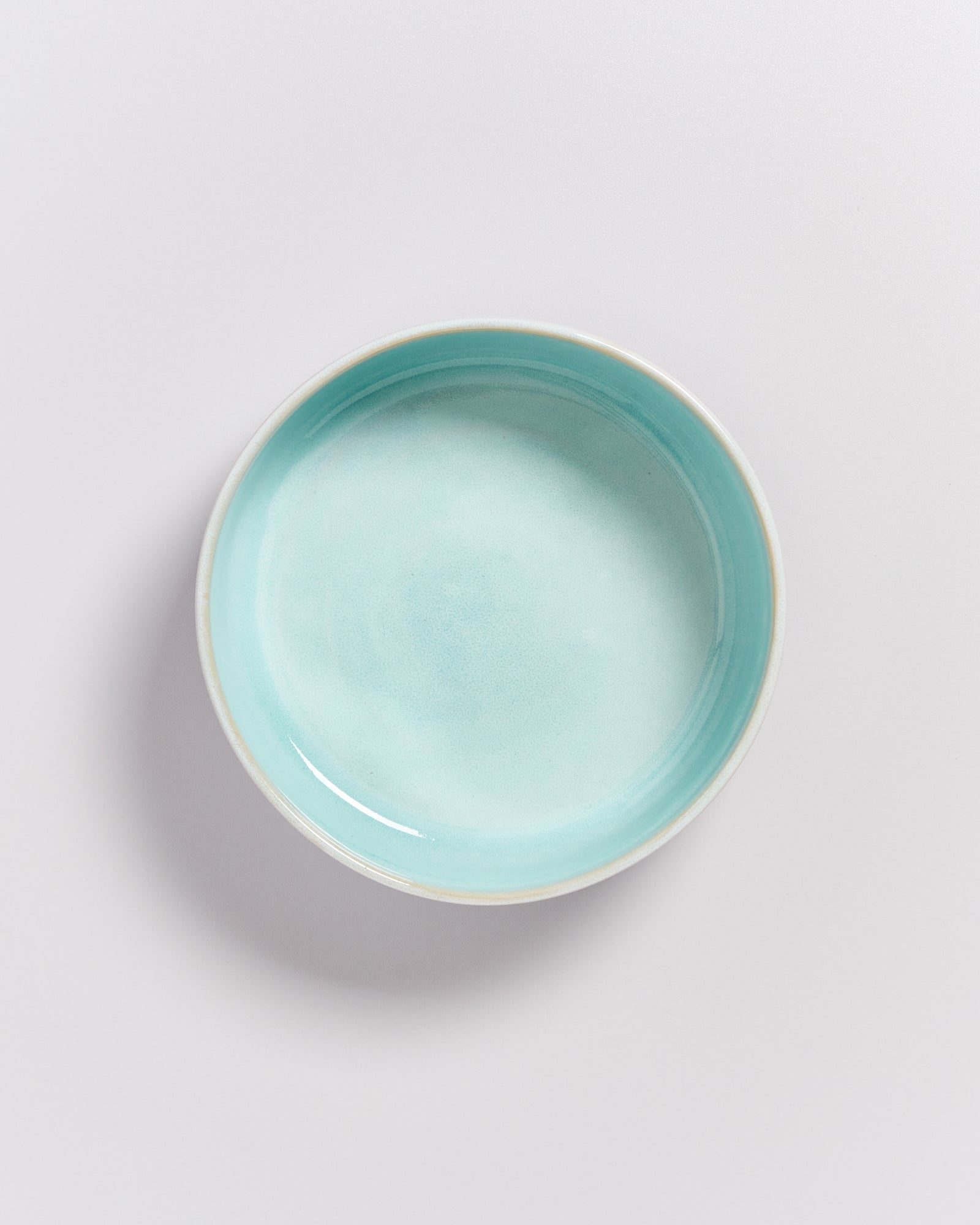 Runde, türkisfarbene Schale auf weißem Hintergrund.