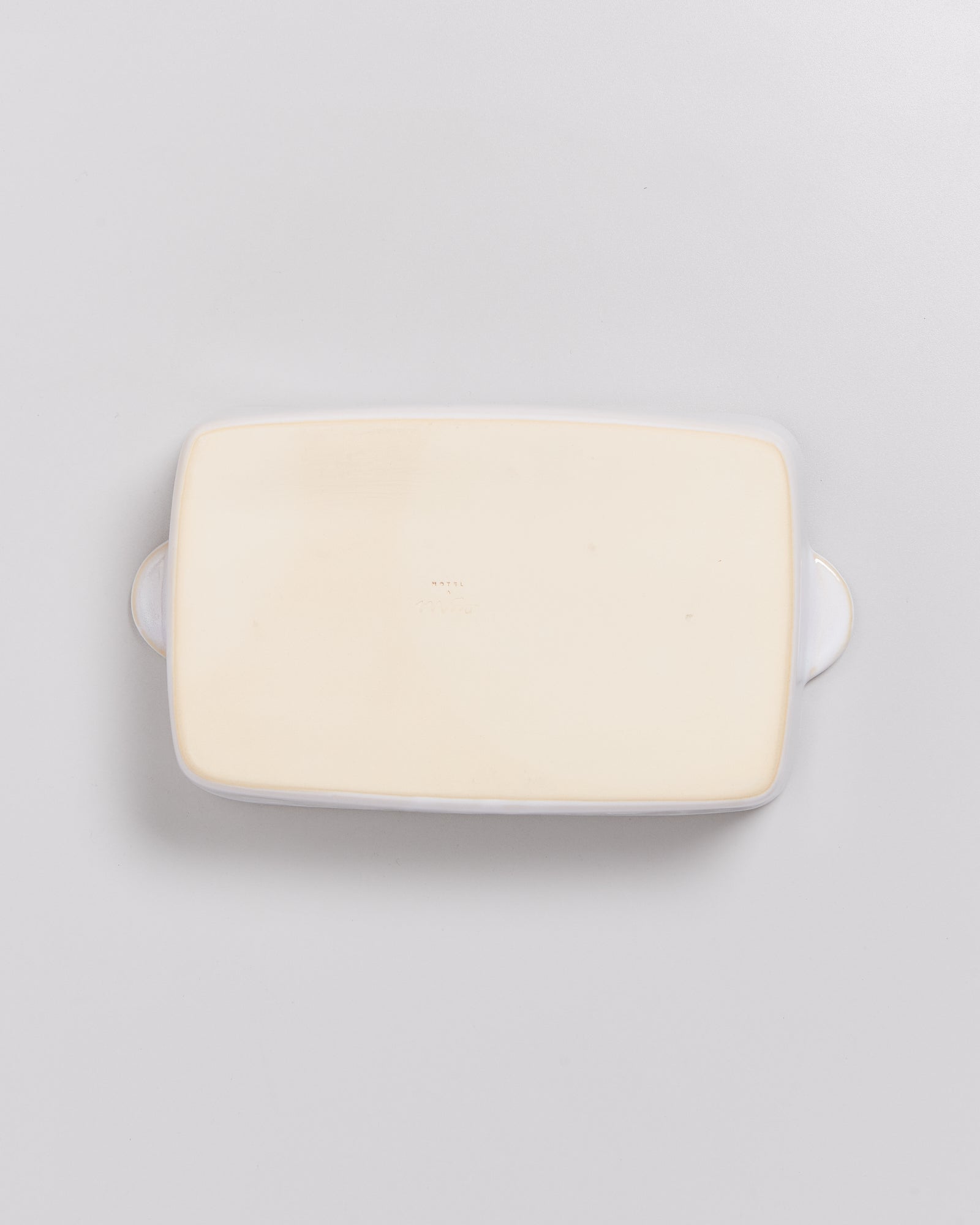 Rechteckige, flache Porzellanschale mit Griffen, Ansicht von unten auf weißem Hintergrund.