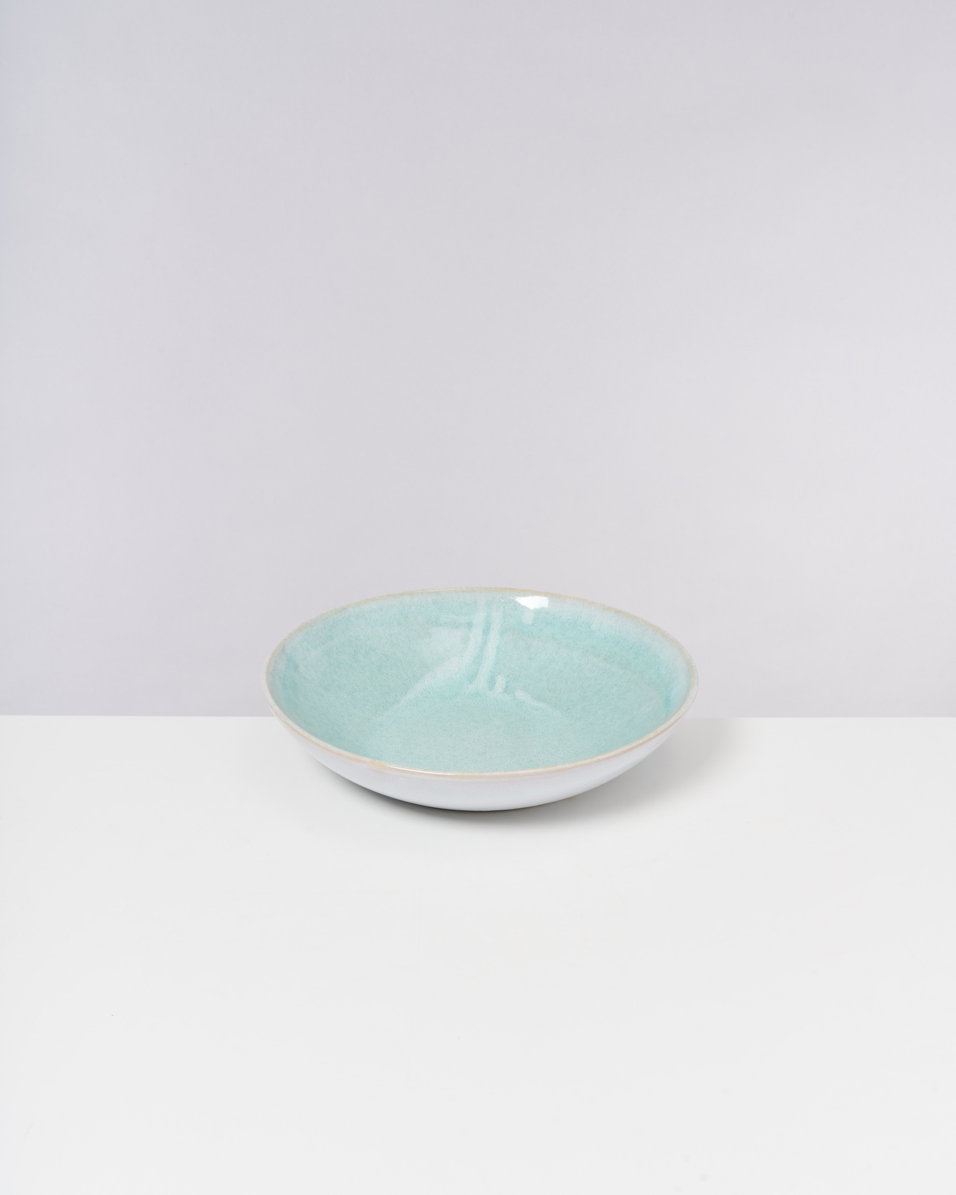 Hellblaue, runde Keramikschale auf weißem Hintergrund.