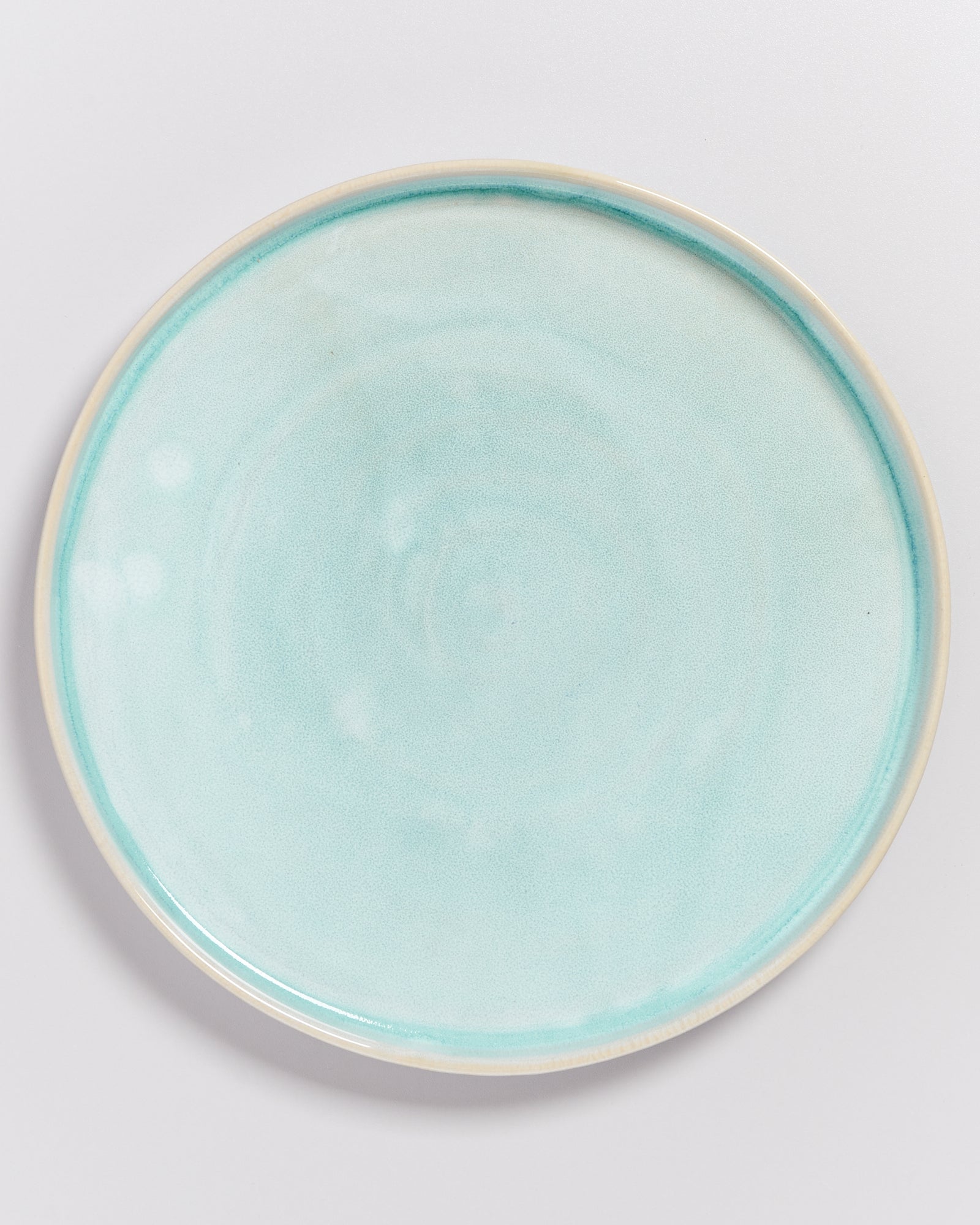 Ein hellblauer Keramikteller mit glatter Oberfläche vor einem weißen Hintergrund.