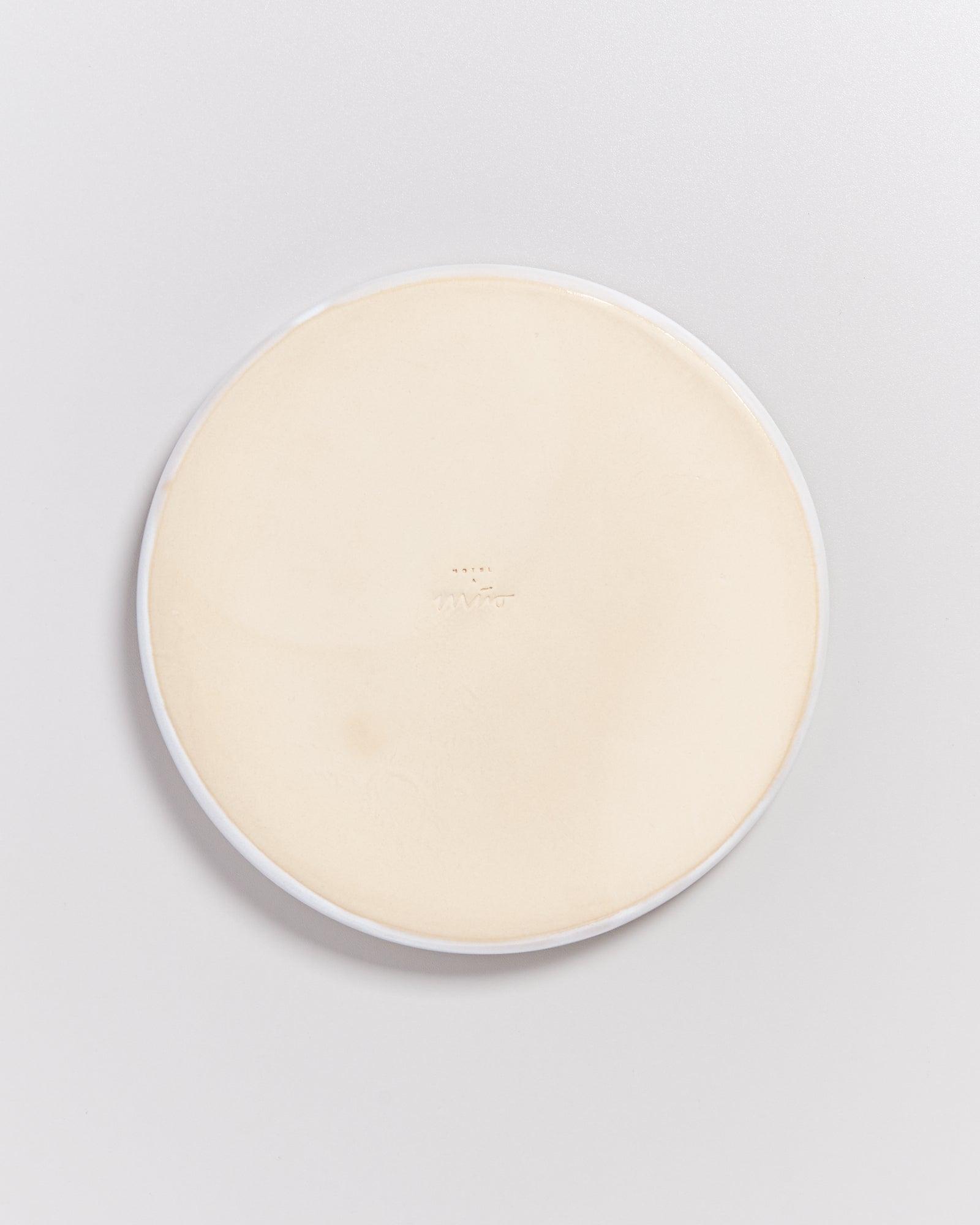 Runde, beige Seifenschale mit weißem Rand auf einem weißen Hintergrund.