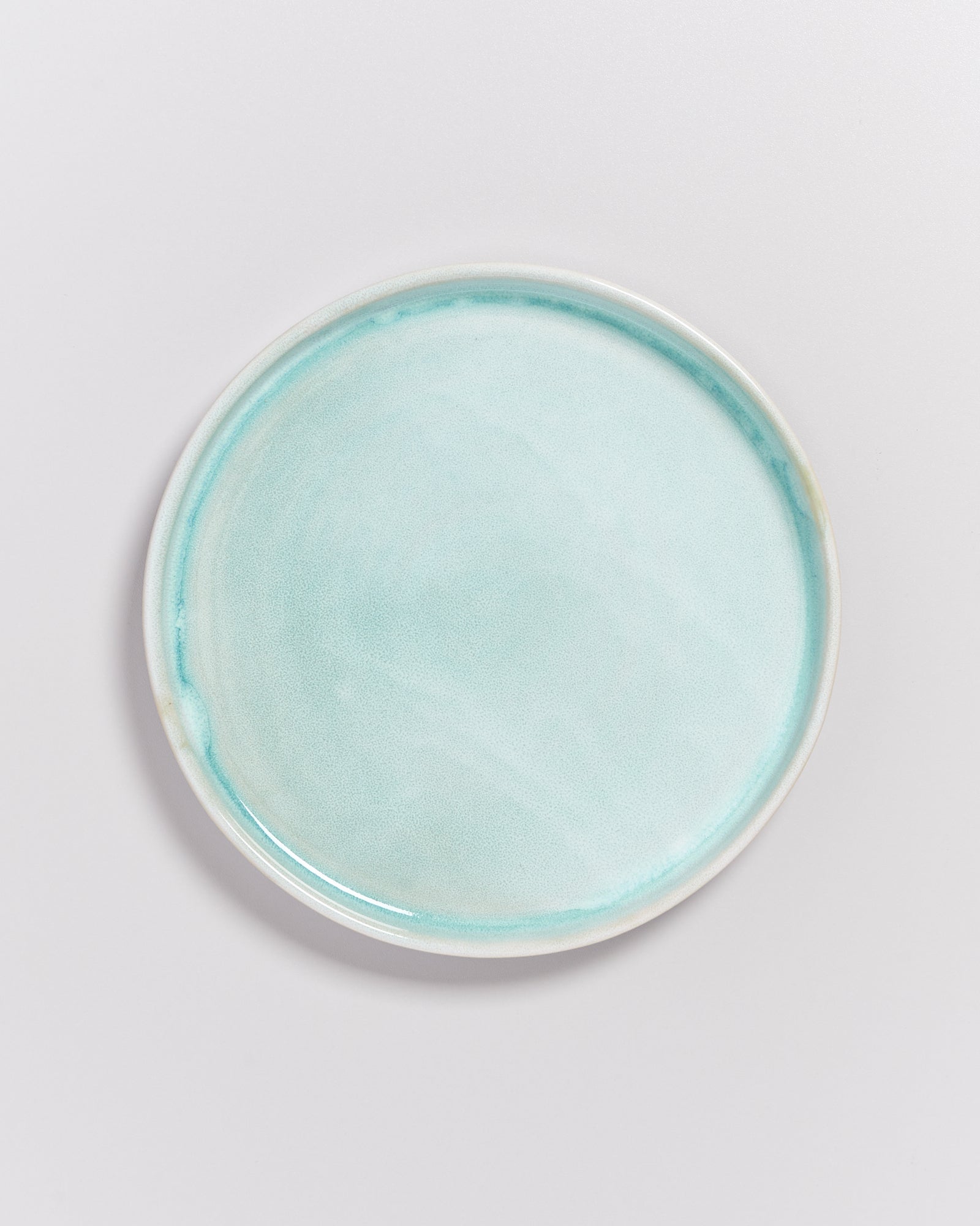 Ein runder, heller hellblauer Teller auf einem weißen Hintergrund.