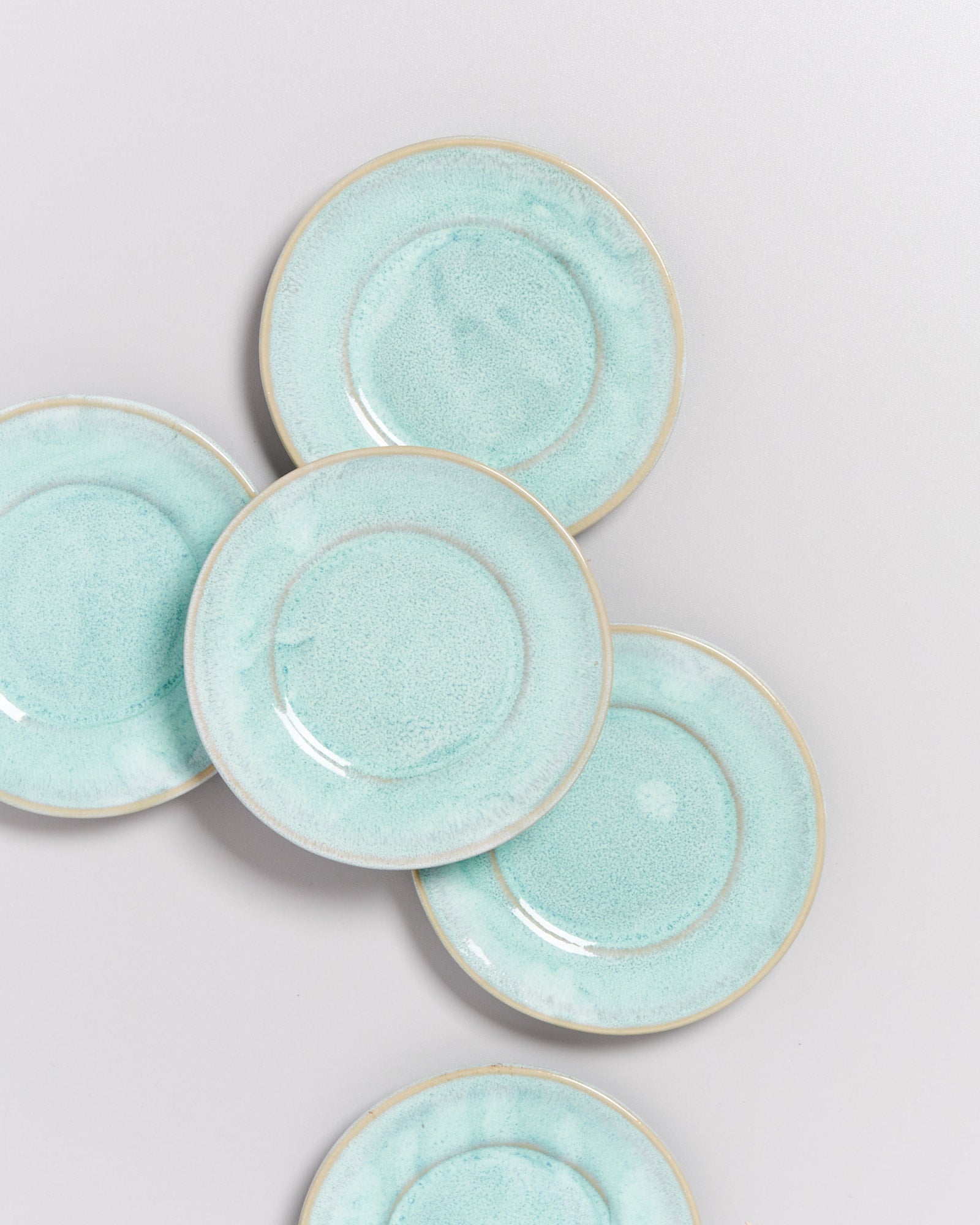 Fünf hellblaue Keramikteller mit einem leicht gesprenkelten Muster auf einem weißen Hintergrund.