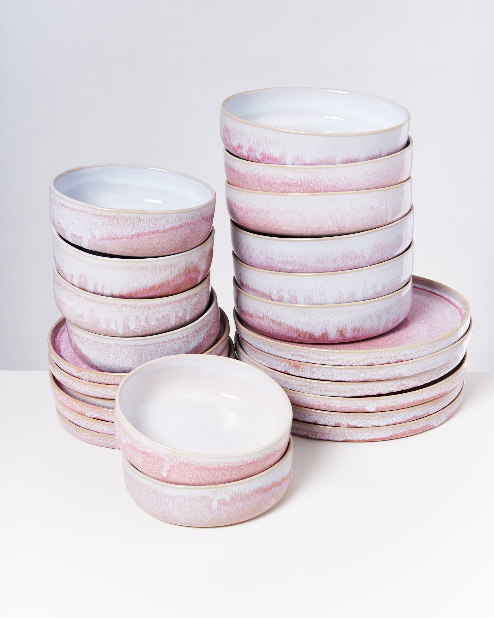 Ein Stapel rosa-weißer Keramikteller steht auf einer weißen Oberfläche.