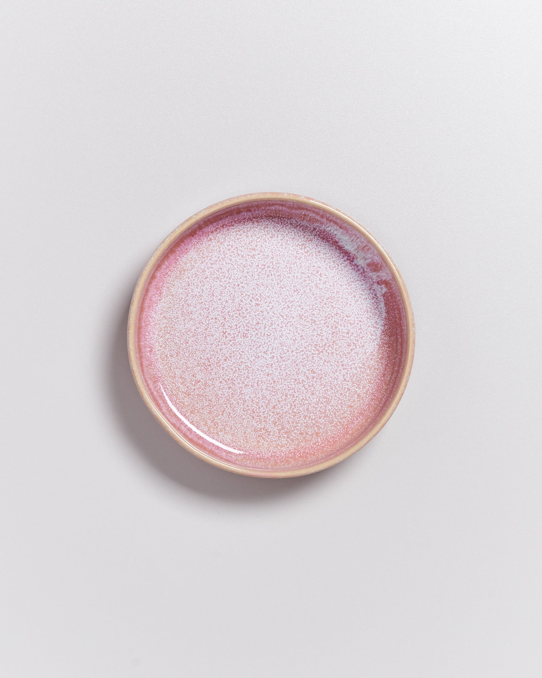 Keramikschale mit rosa und weißen Sprenkeln auf hellem Hintergrund.