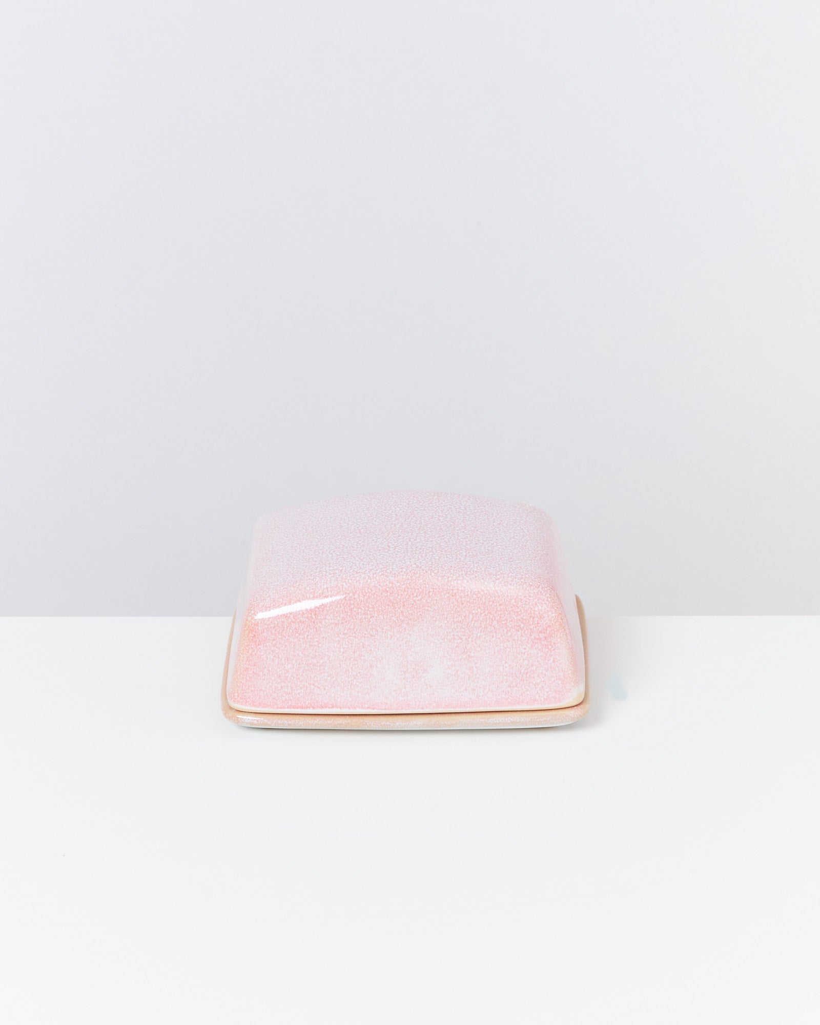 Rosa, rechteckige Porzellanschale mit Deckel auf einem weißen Hintergrund.