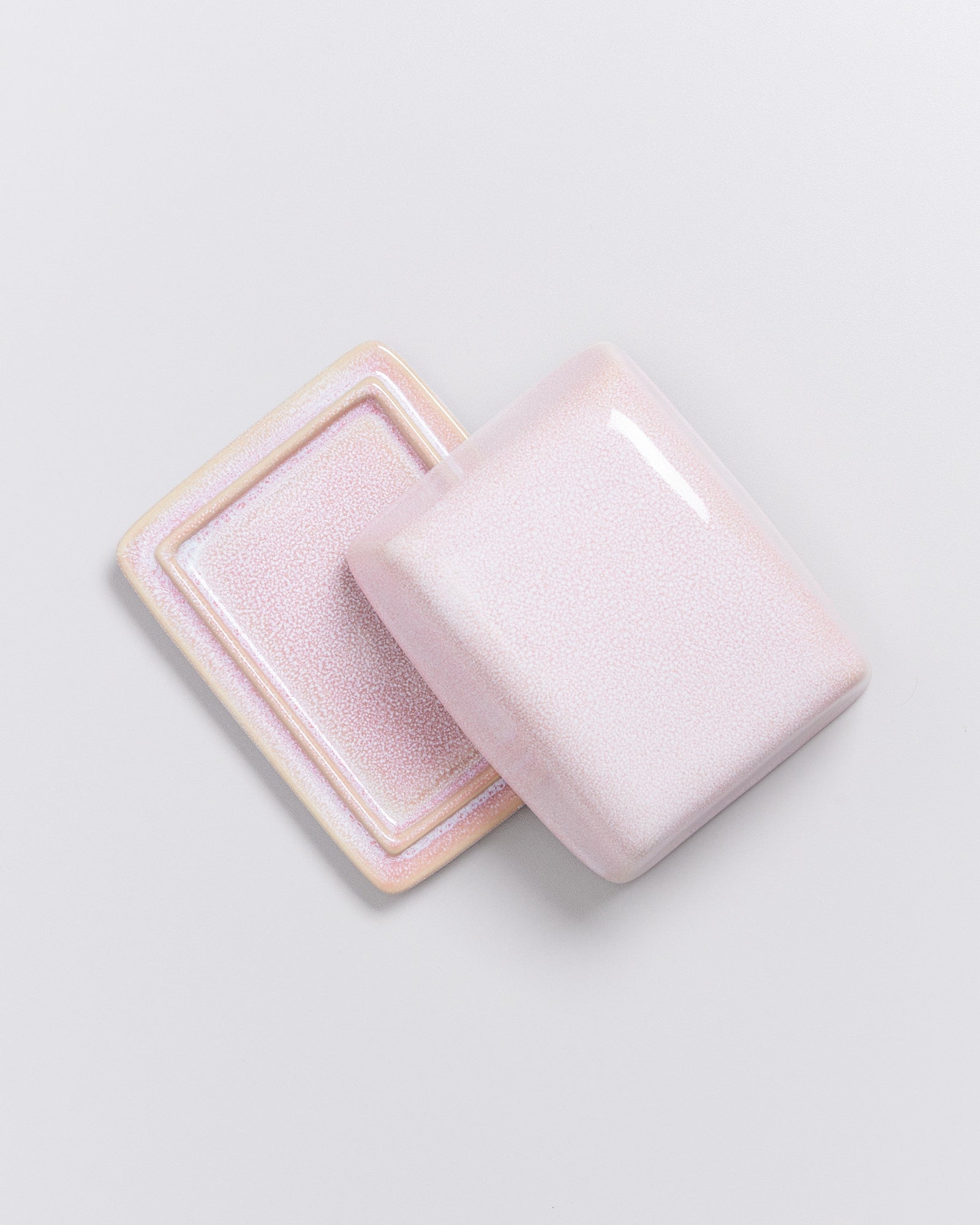 Zwei übereinander liegende, rechteckige Keramikplatten in hellem Rosa auf einem weißen Hintergrund.