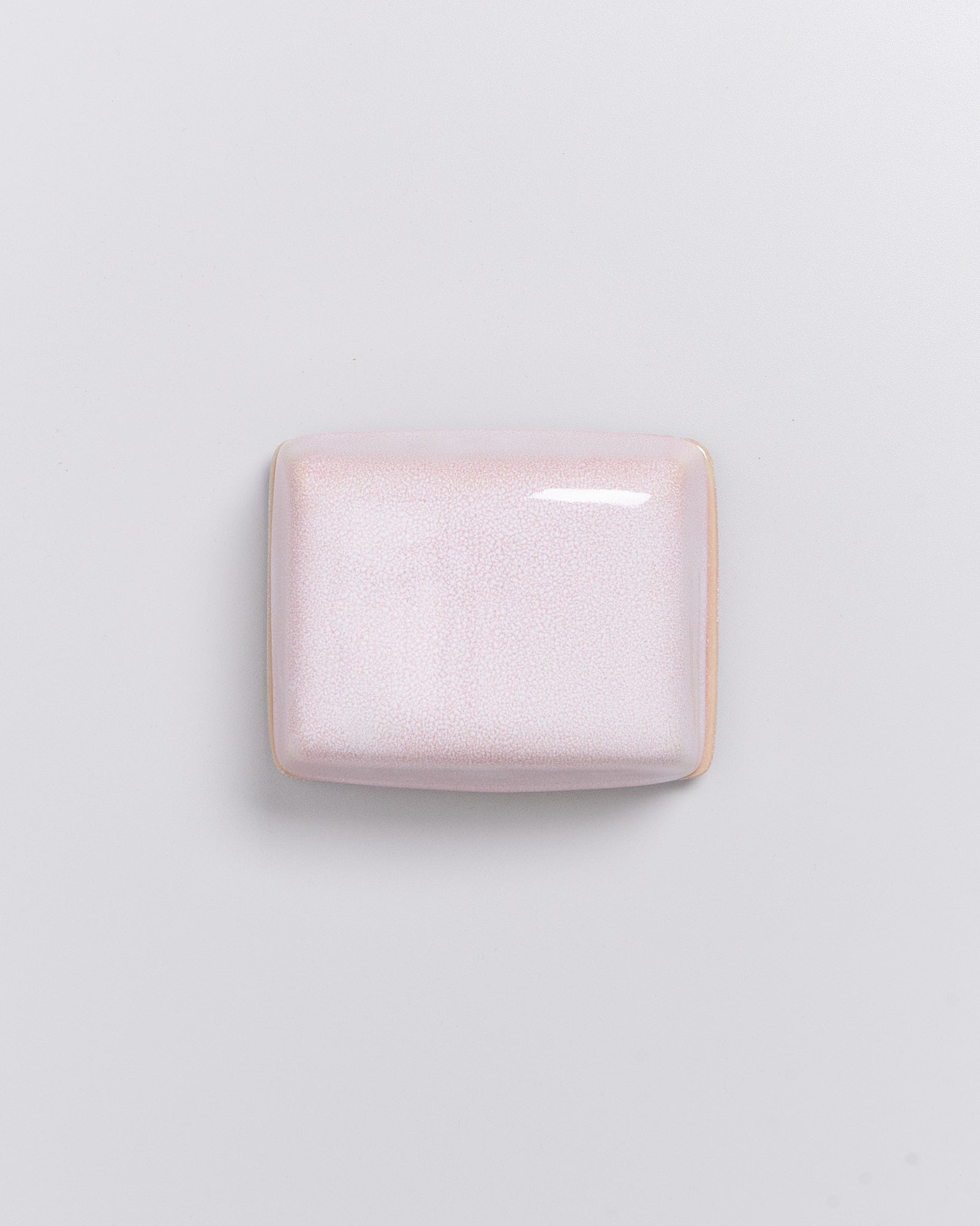 Rechteckige rosa Seife mit glatter Oberfläche auf weißem Hintergrund.