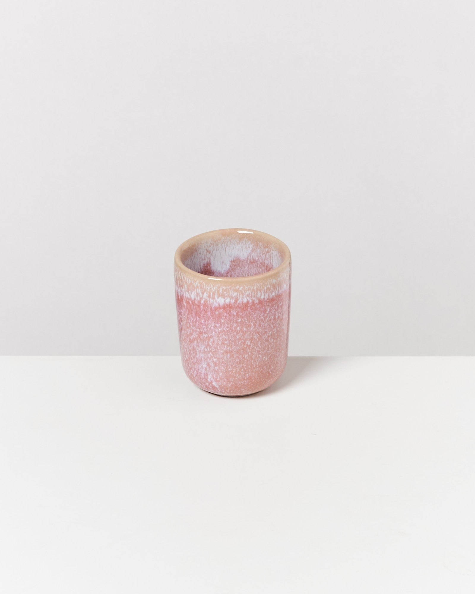 Keramikbecher mit rosa-weißem Farbverlauf auf weißem Hintergrund.