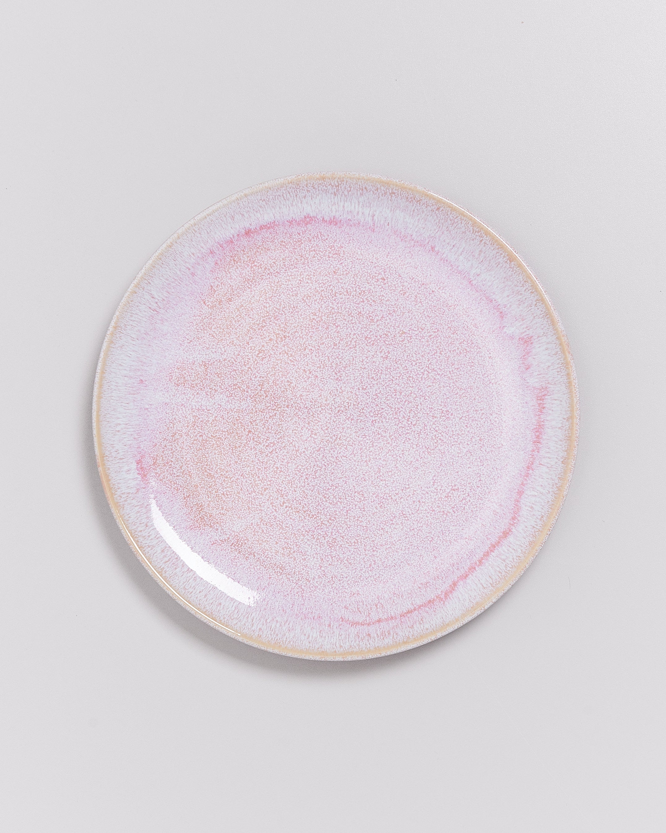 Runder Teller mit rosa Sprenkelmuster auf hellem Hintergrund.