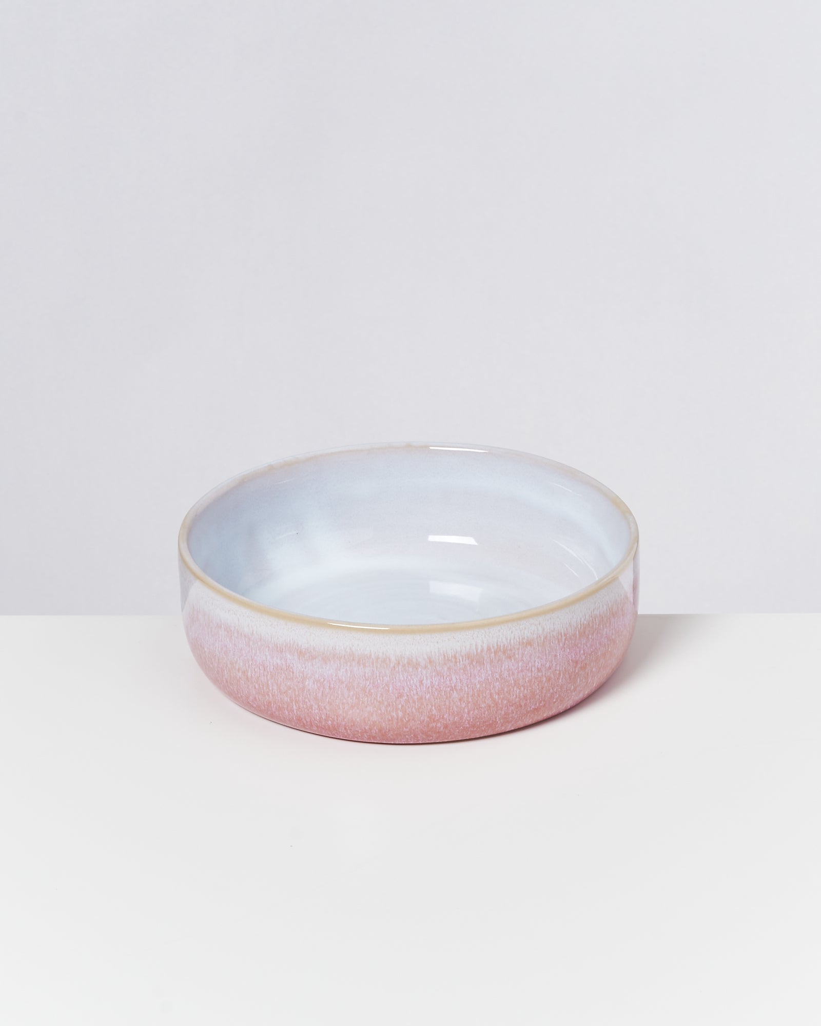 Keramikschale mit rosa und blauer Glasur auf weißem Hintergrund.