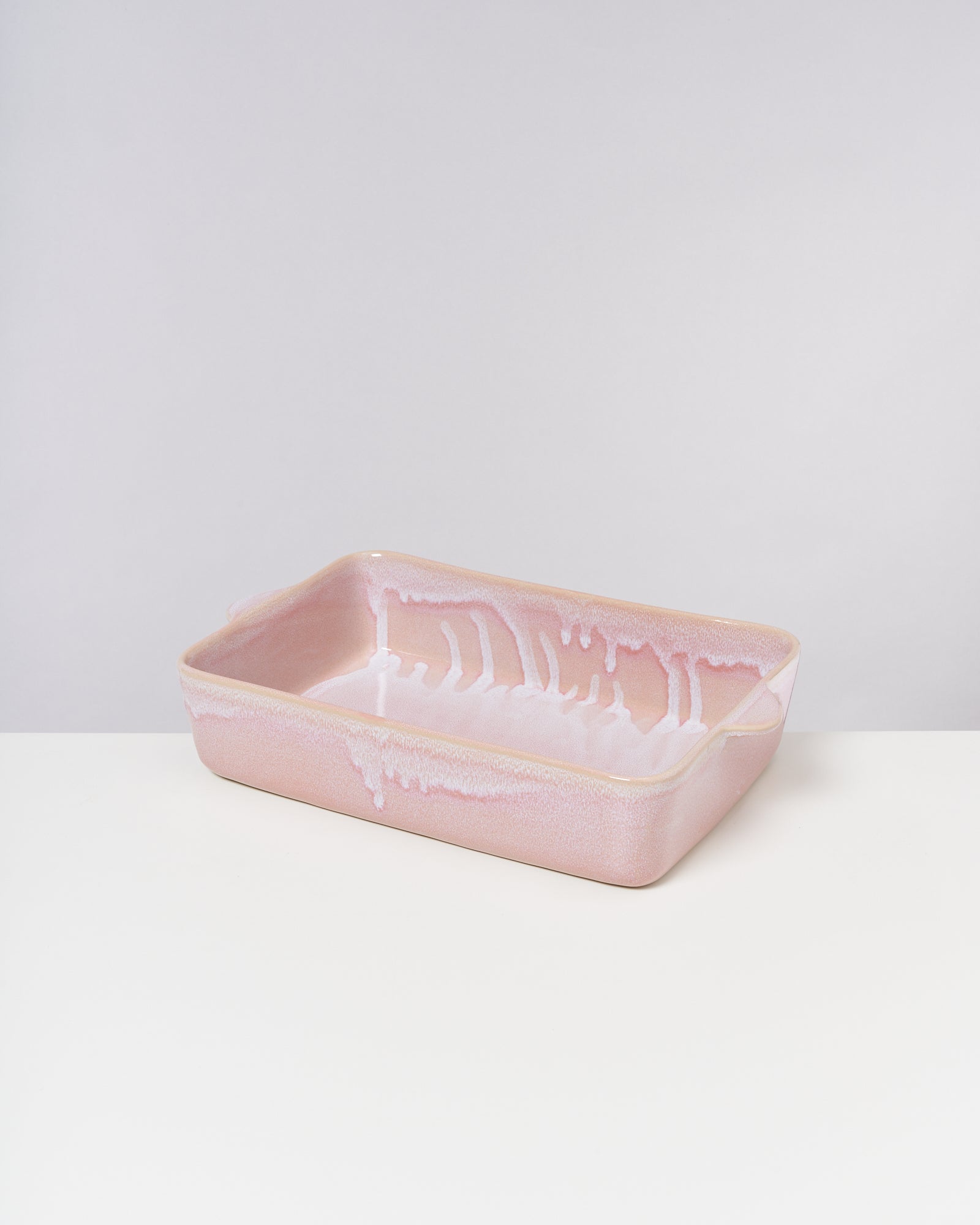 Rechteckige, rosa Auflaufform mit weißem, tropfendem Muster auf hellem Hintergrund.