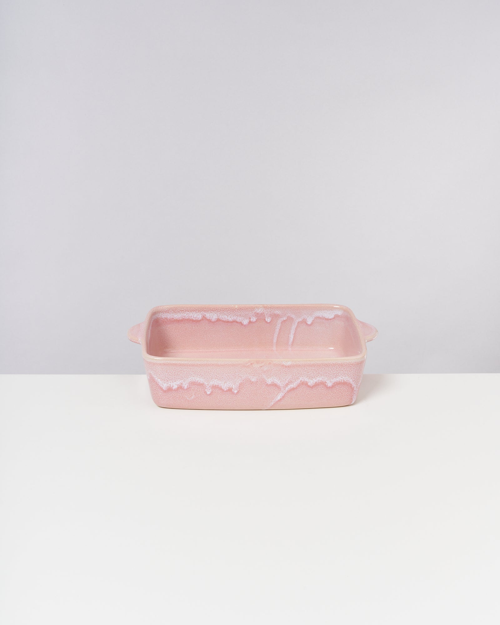Rechteckige rosafarbene Auflaufform mit dekorativen Mustern auf einem weißen Hintergrund.