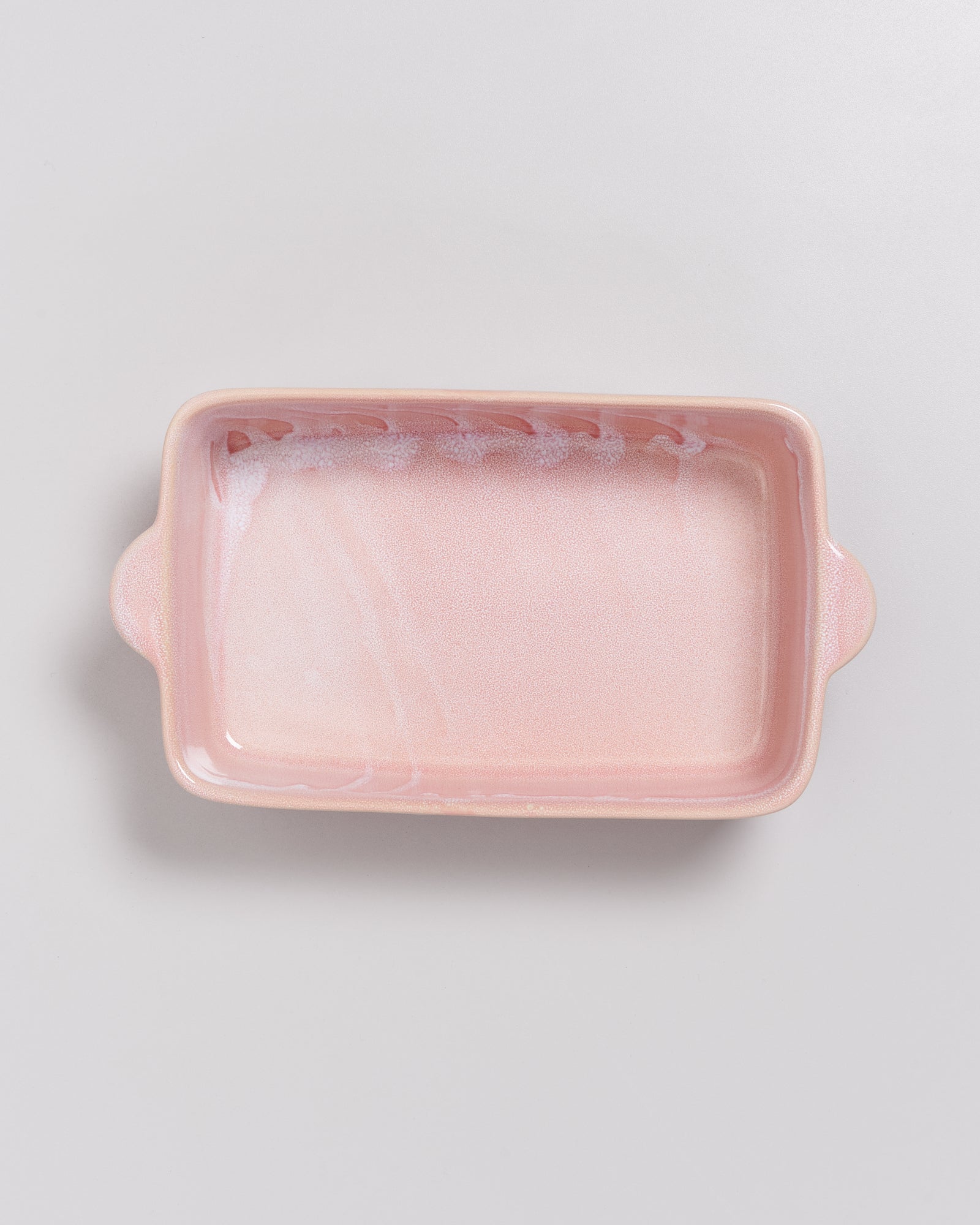 Rosa rechteckige Keramikauflaufform auf grauem Hintergrund.