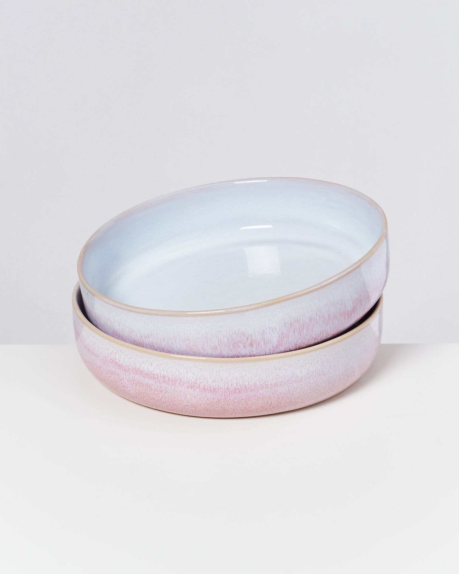 Zwei gestapelte, pastellfarbene Keramikteller auf weißem Hintergrund.