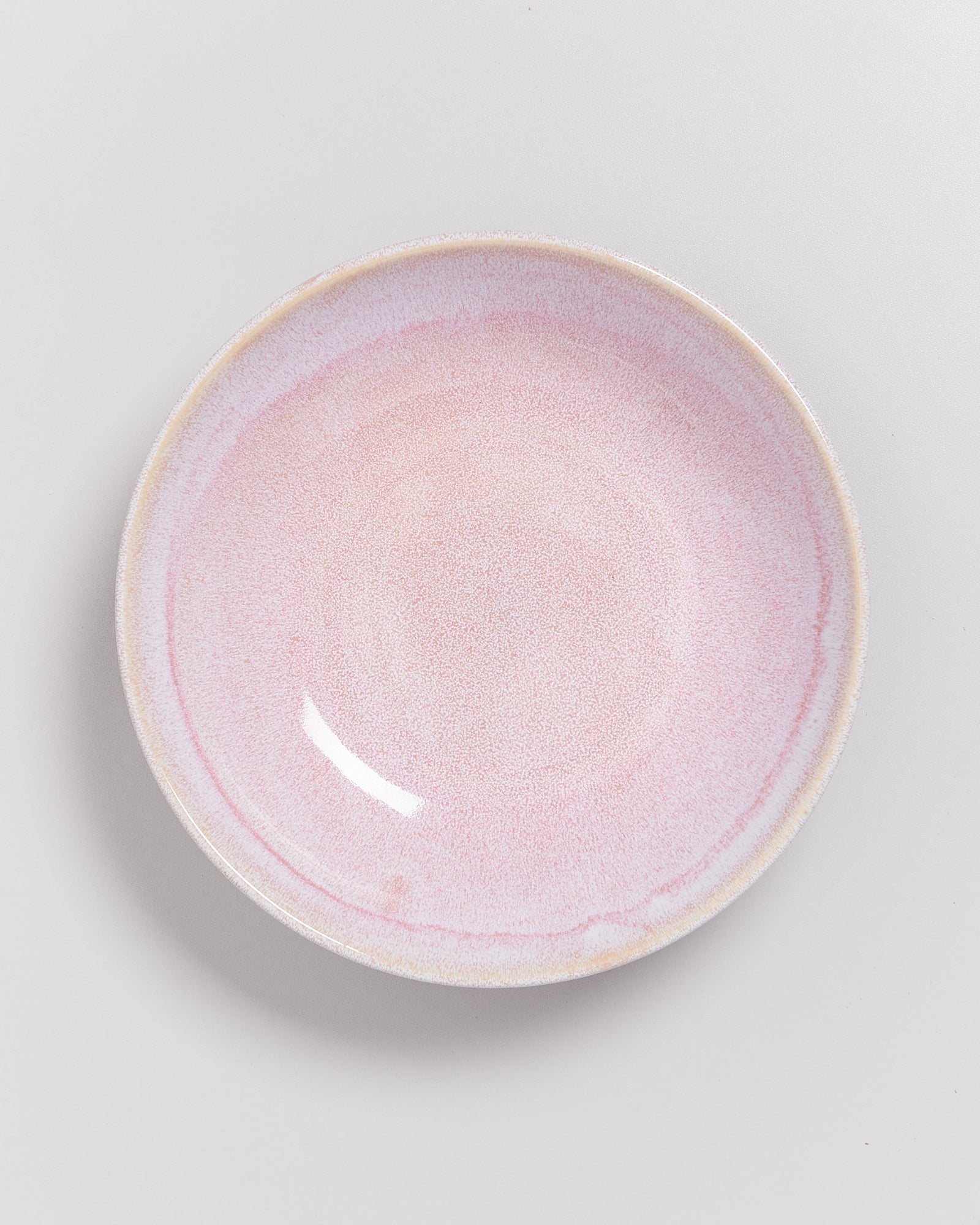 Ein runder, rosa Teller mit leichtem Farbverlauf auf weißem Hintergrund.