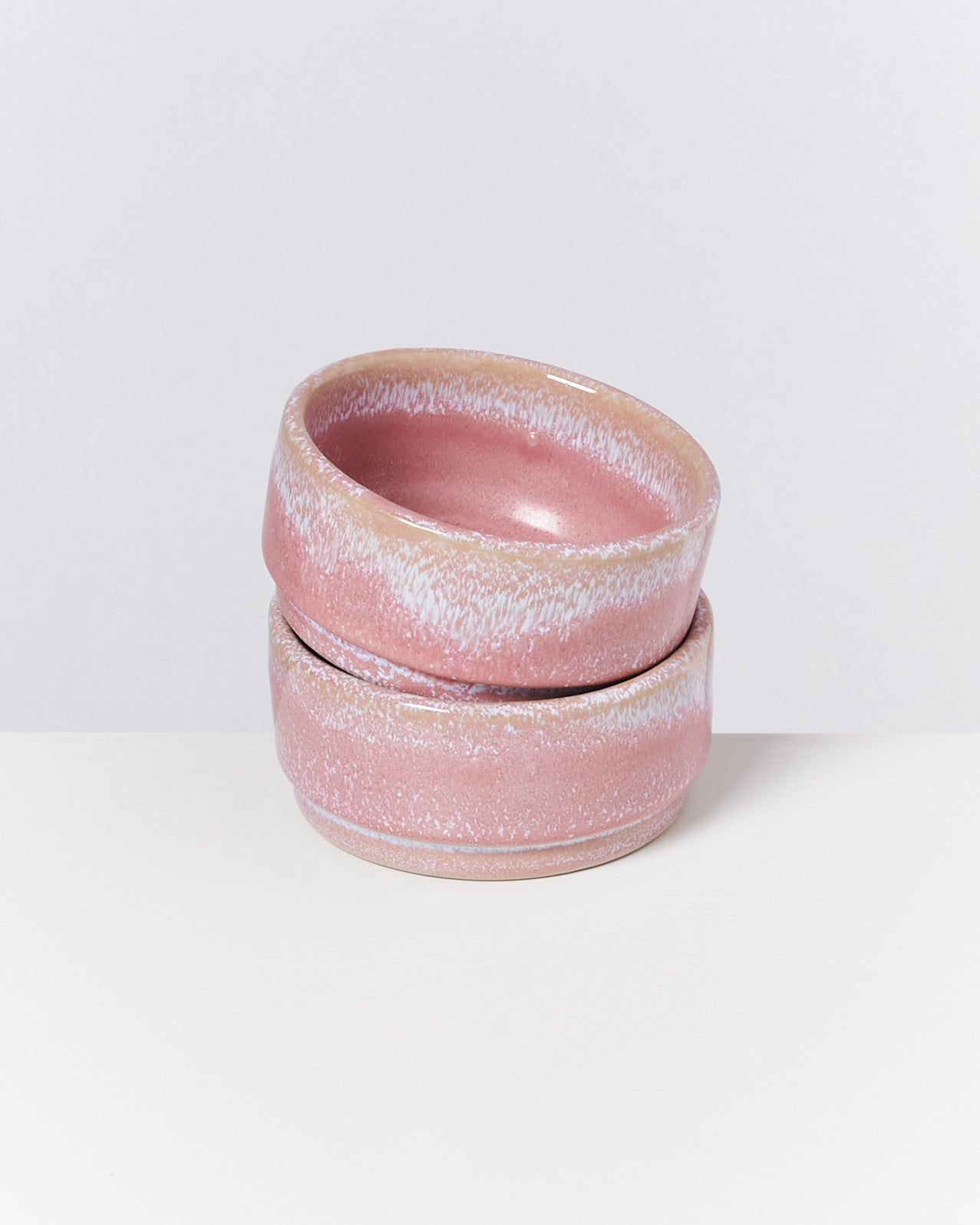 Zwei gestapelte rosa Keramikschalen auf weißem Hintergrund.