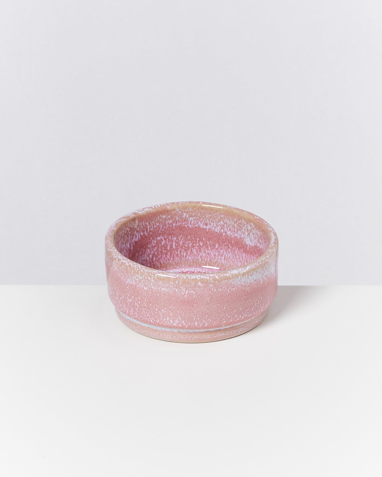 Rosa Keramikschale mit weiß gesprenkeltem Muster auf einem weißen Hintergrund.