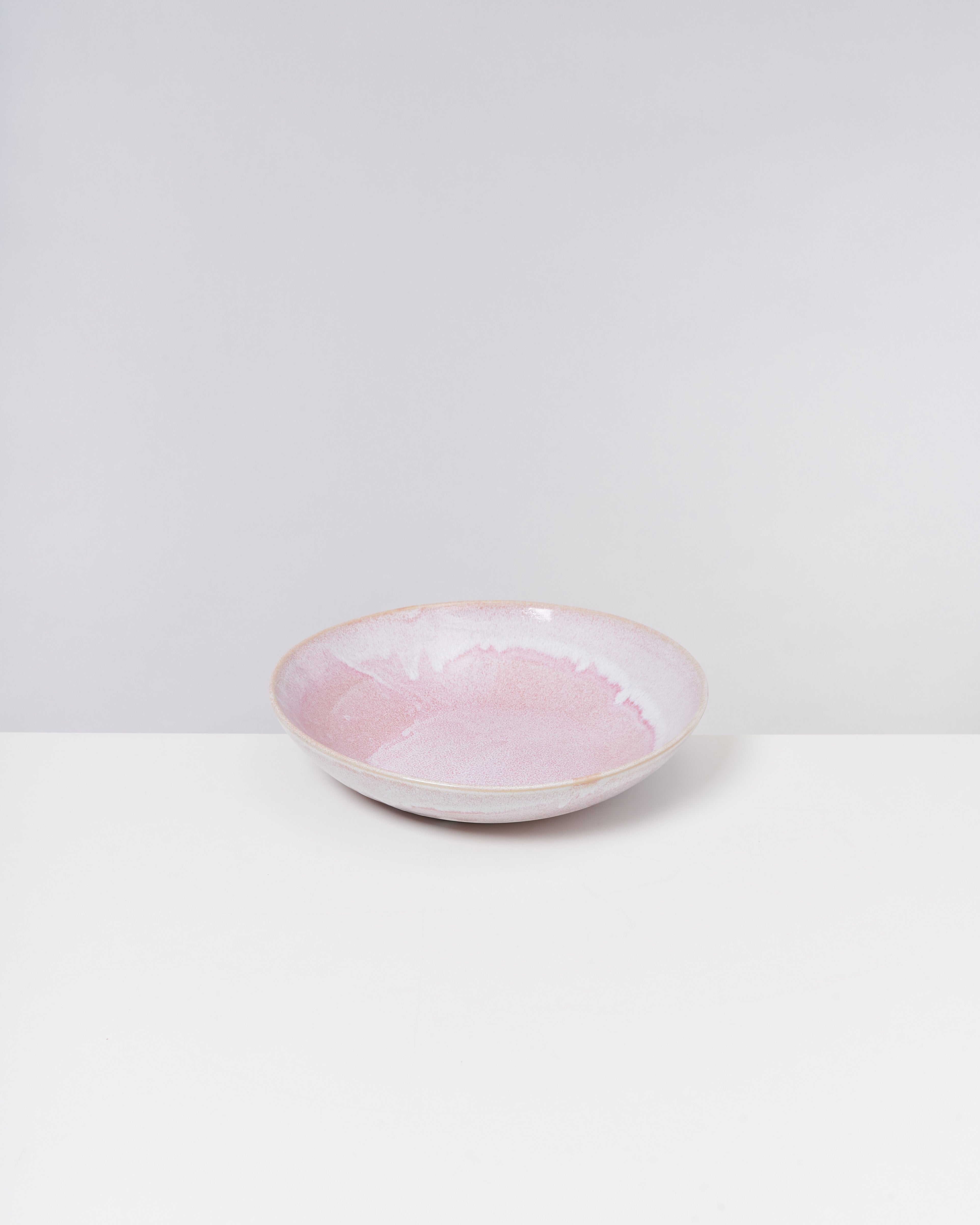 Rosa Keramikschale auf weißem Hintergrund mit dezenten Farbverläufen in Pastelltönen.