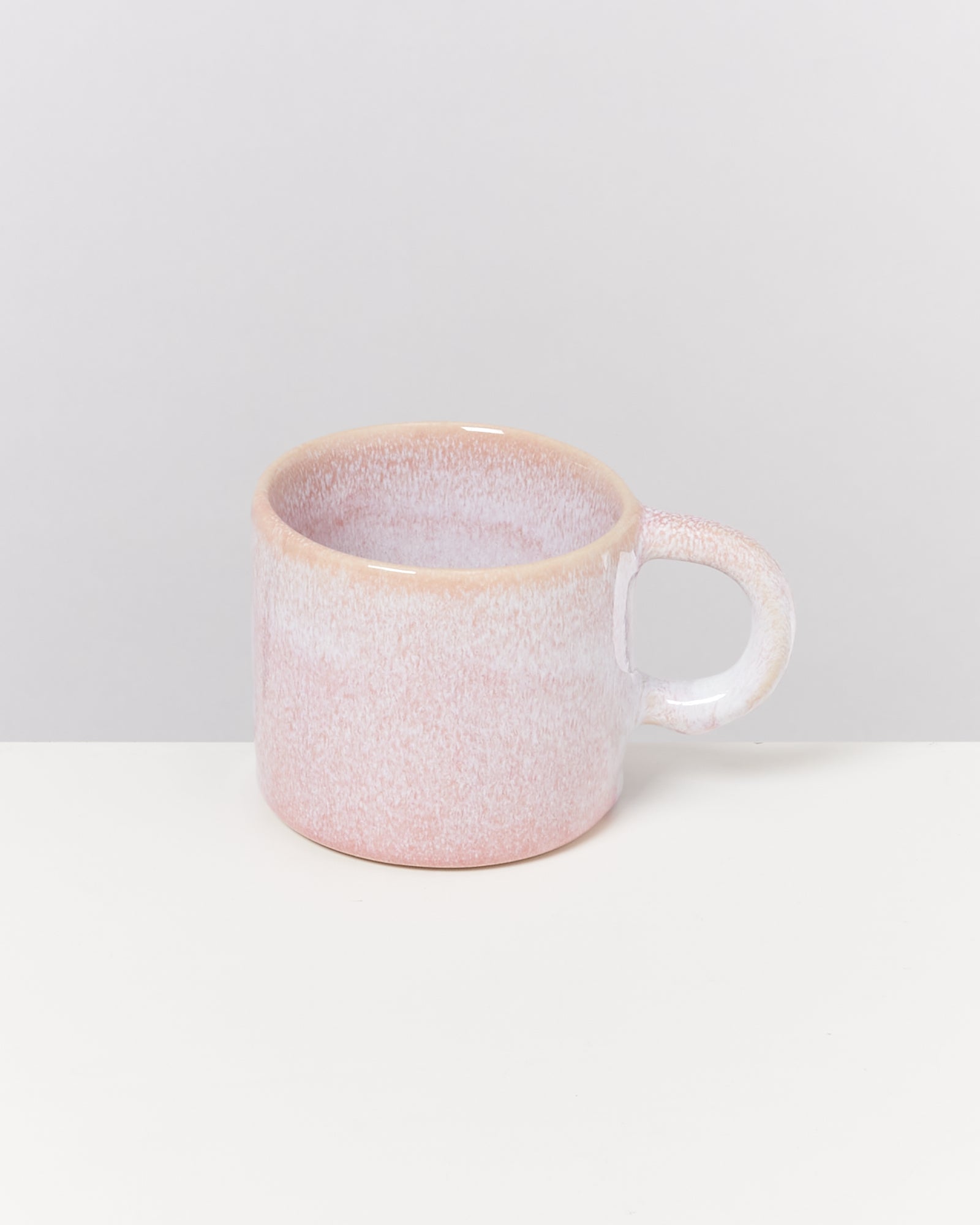 Rosa Keramiktasse mit Henkel auf weißem Hintergrund.