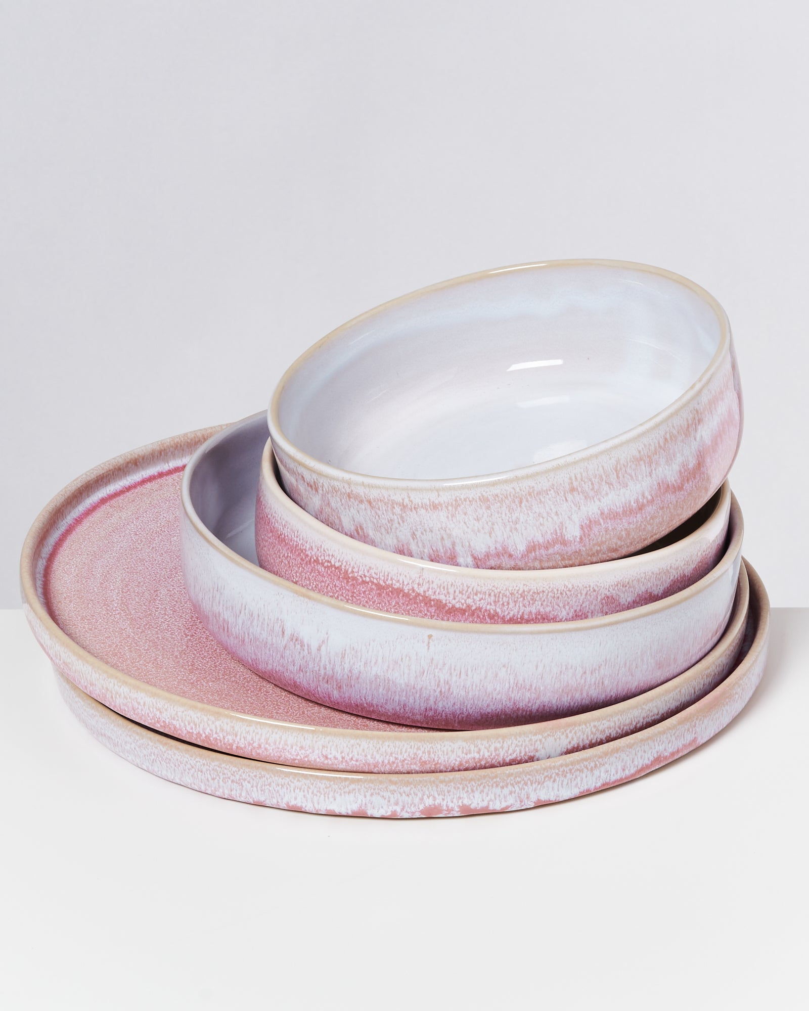 Ein Stapel von vier runden, rosafarbenen Tellern vor einem weißen Hintergrund.