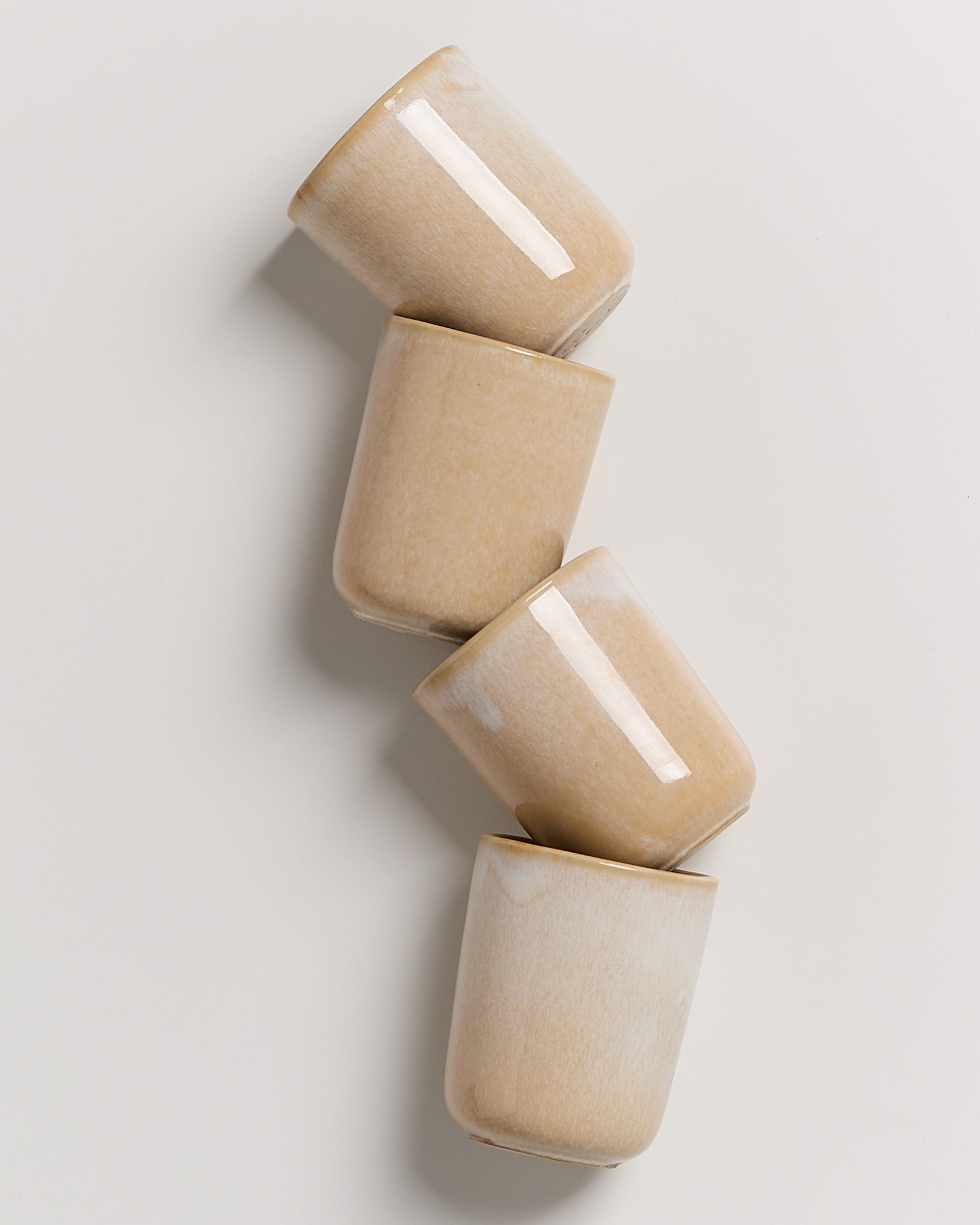 Vier beige stapelbare Keramikbecher auf einem weißen Hintergrund.