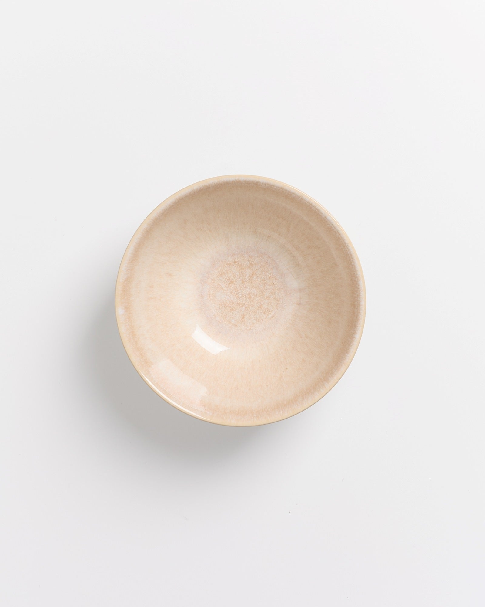 Beiger Keramikteller auf weißem Hintergrund, von oben betrachtet.
