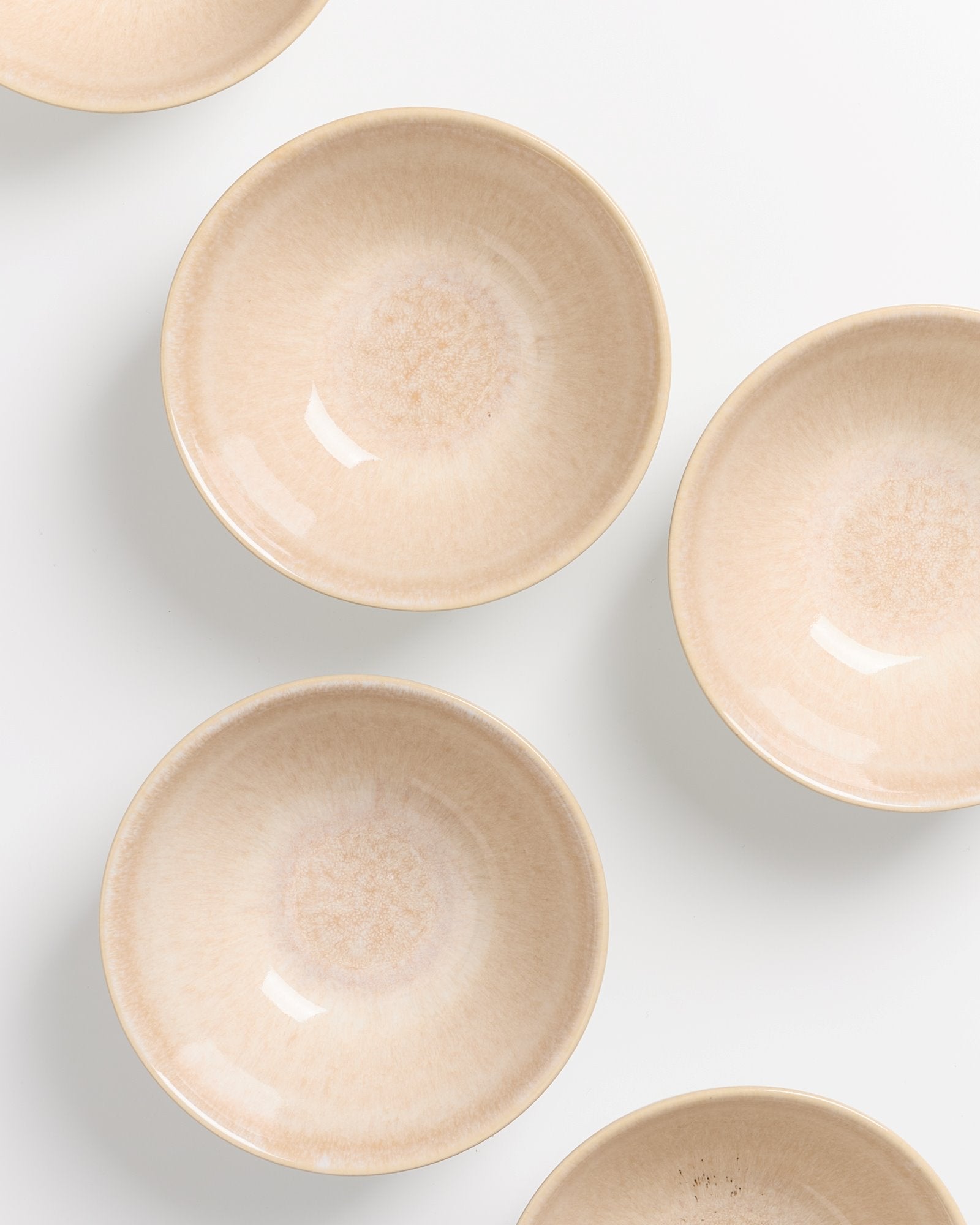 Sechs beige Schalen sind auf einem weißen Hintergrund symmetrisch angeordnet.