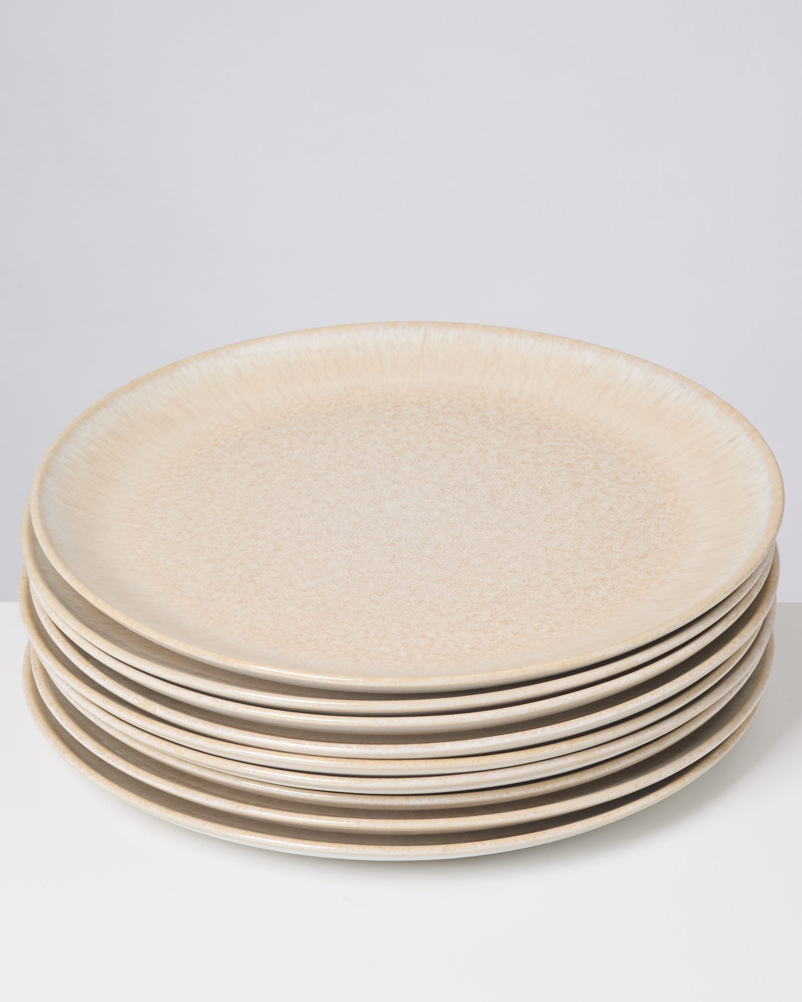 Ein Stapel aus sieben beigen Tellern steht auf einem weißen Hintergrund.