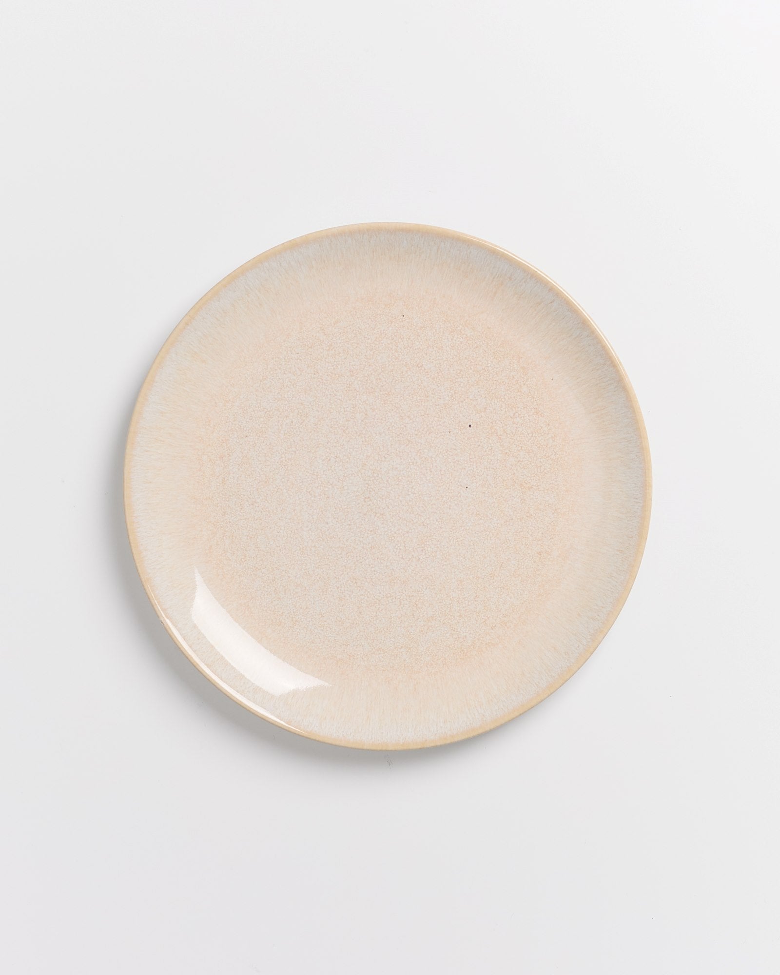 Beiger, runder Keramikteller auf weißem Hintergrund.