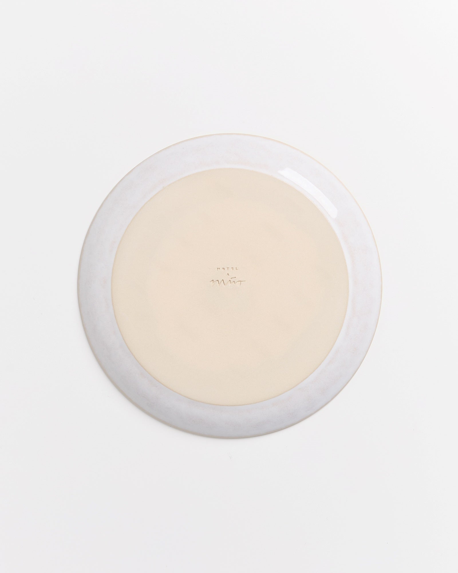 Die Rückseite eines cremefarbenen Tellers mit leichtem Rand auf weißem Hintergrund.