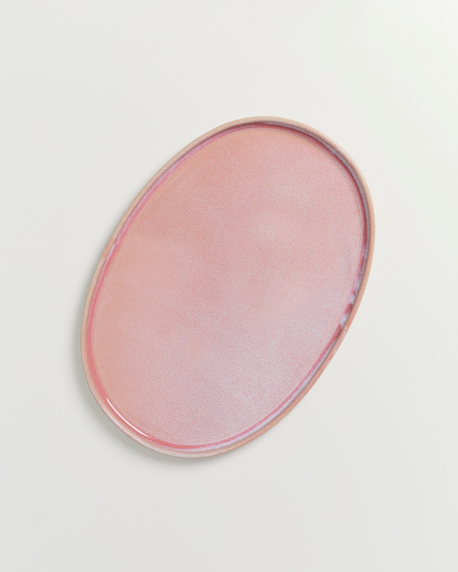 Ovale, rosafarbene Keramikplatte auf weißem Hintergrund.