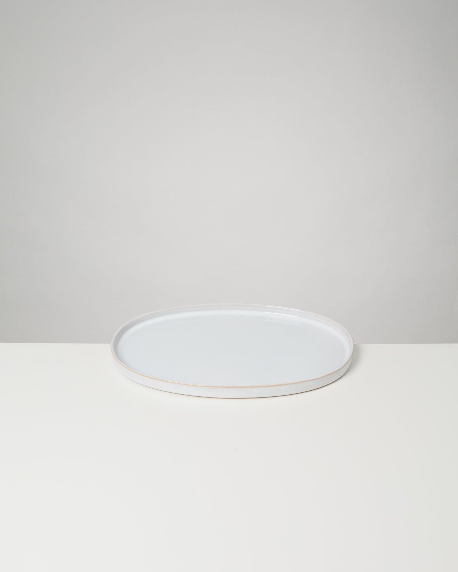 Ein weißer, ovaler Teller auf einem hellen Hintergrund.