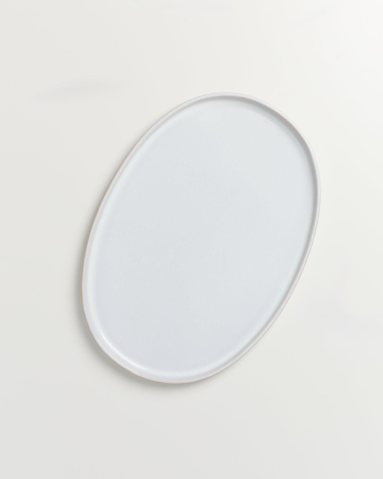 Ovaler, weißer Teller auf einem hellen Hintergrund.