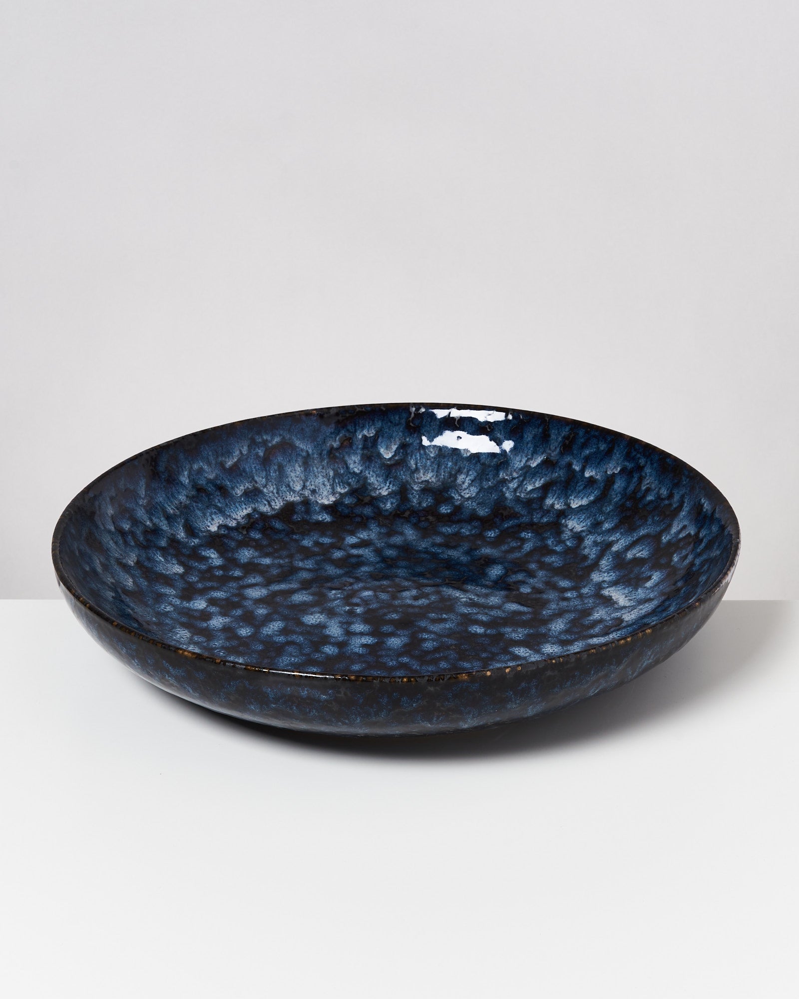 Dunkelblaue, gemusterte Keramikschale auf weißem Hintergrund.
